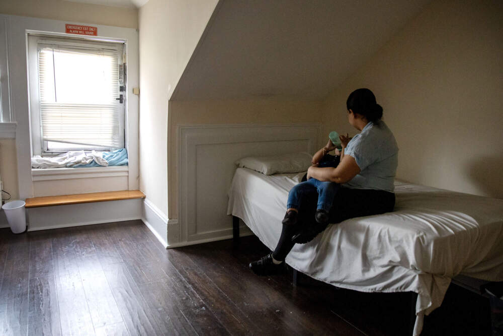 Ericka Guerrero gives her son, Leudi, a bottle in their shelter room in Brookline. (Robin Lubbock/WBUR)