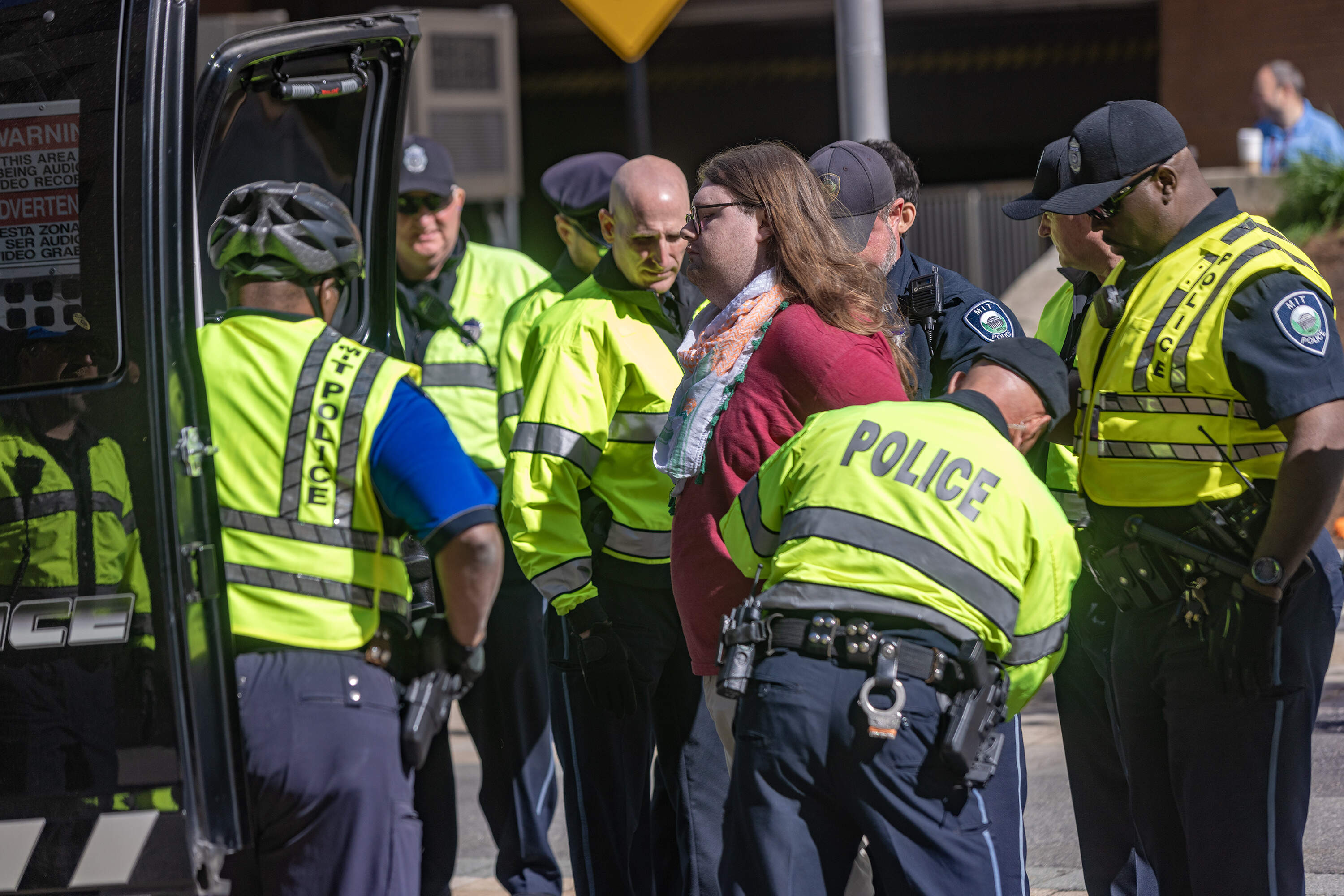 One of the protesters obstructing the entryway of the garage at the Stata Center is handcuffed by MIT Police and is placed into a police wagon. (Jesse Costa/WBUR)