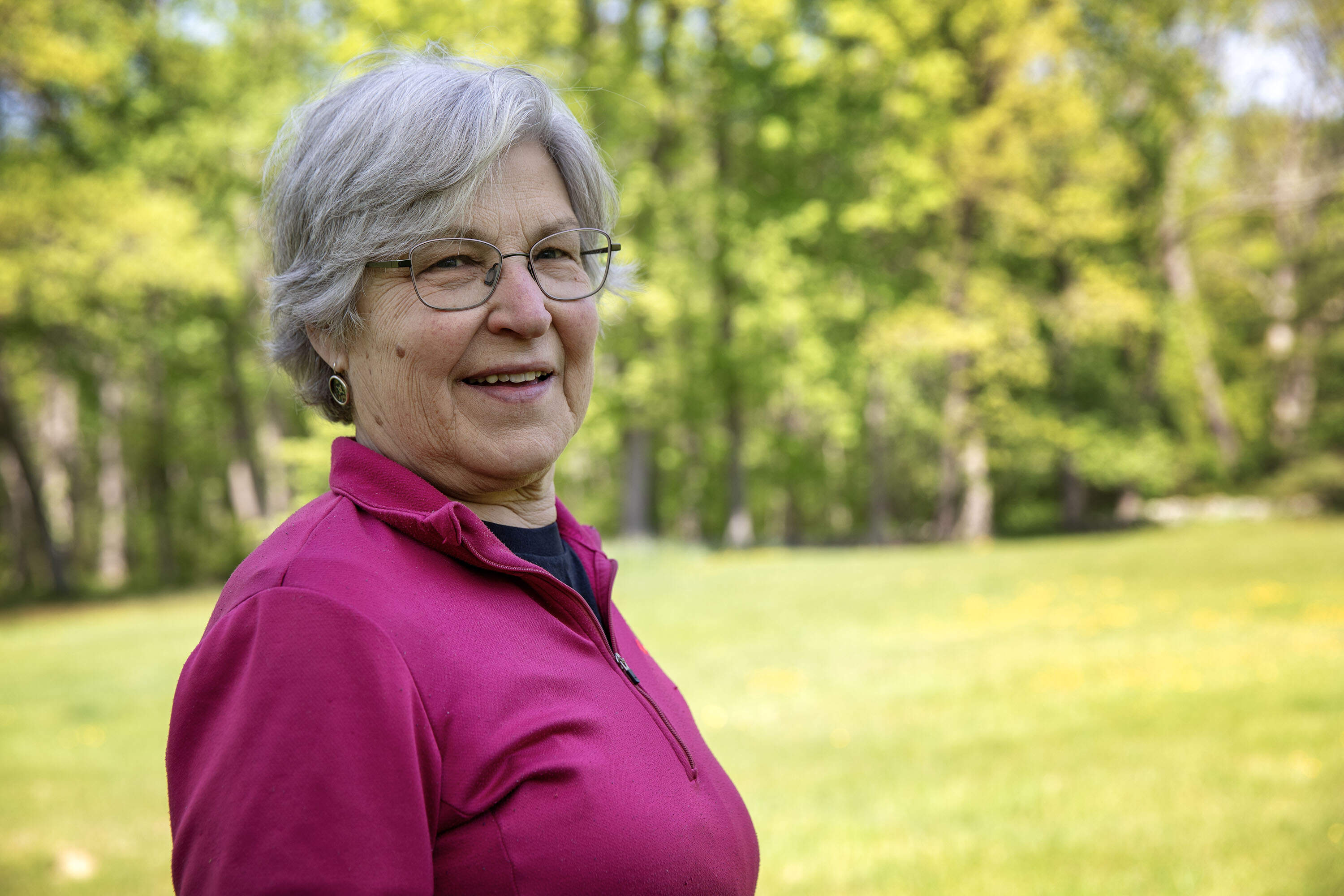 Mary Hollinshead stands surrounded by the fields and woodland around her home, which she aims to conserve. (Robin Lubbock/WBUR)
