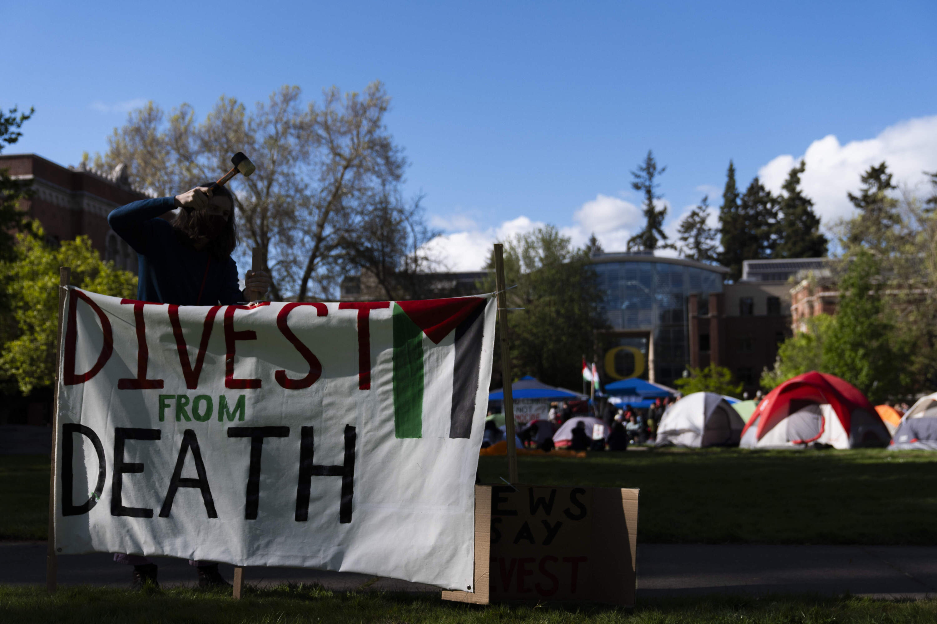 A student at the University of Oregon sets up a sign that reads "Divest from death" as students set up a tent encampment at the university to protest the Israel-Hamas war. (Jenny Kane/AP)