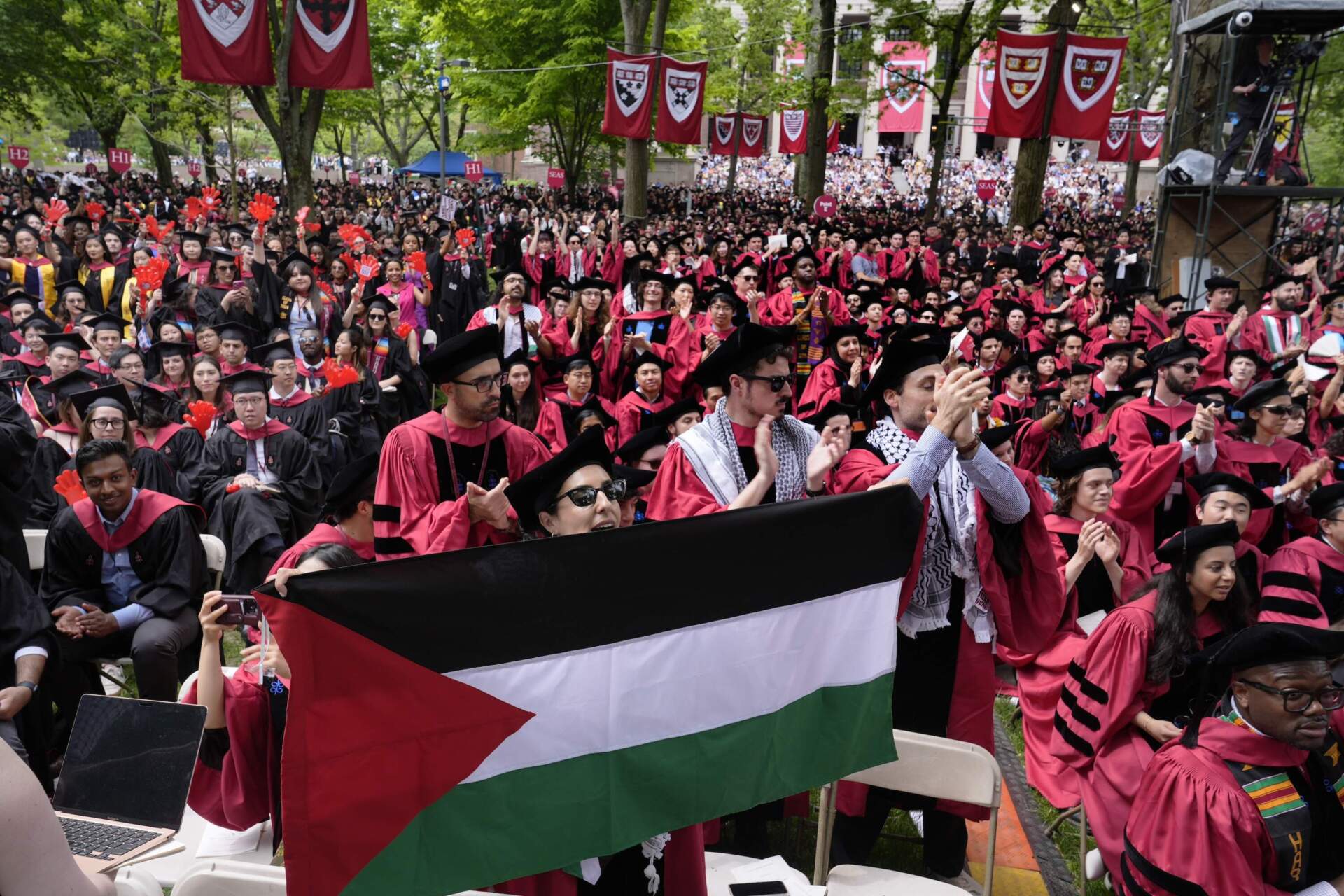 A student holds up the flag of Palestine as the 13 students, who have been barred from graduating due to protest activities, are recognized by a student address speaker during the commencement at Harvard University. (Charles Krupa/AP)