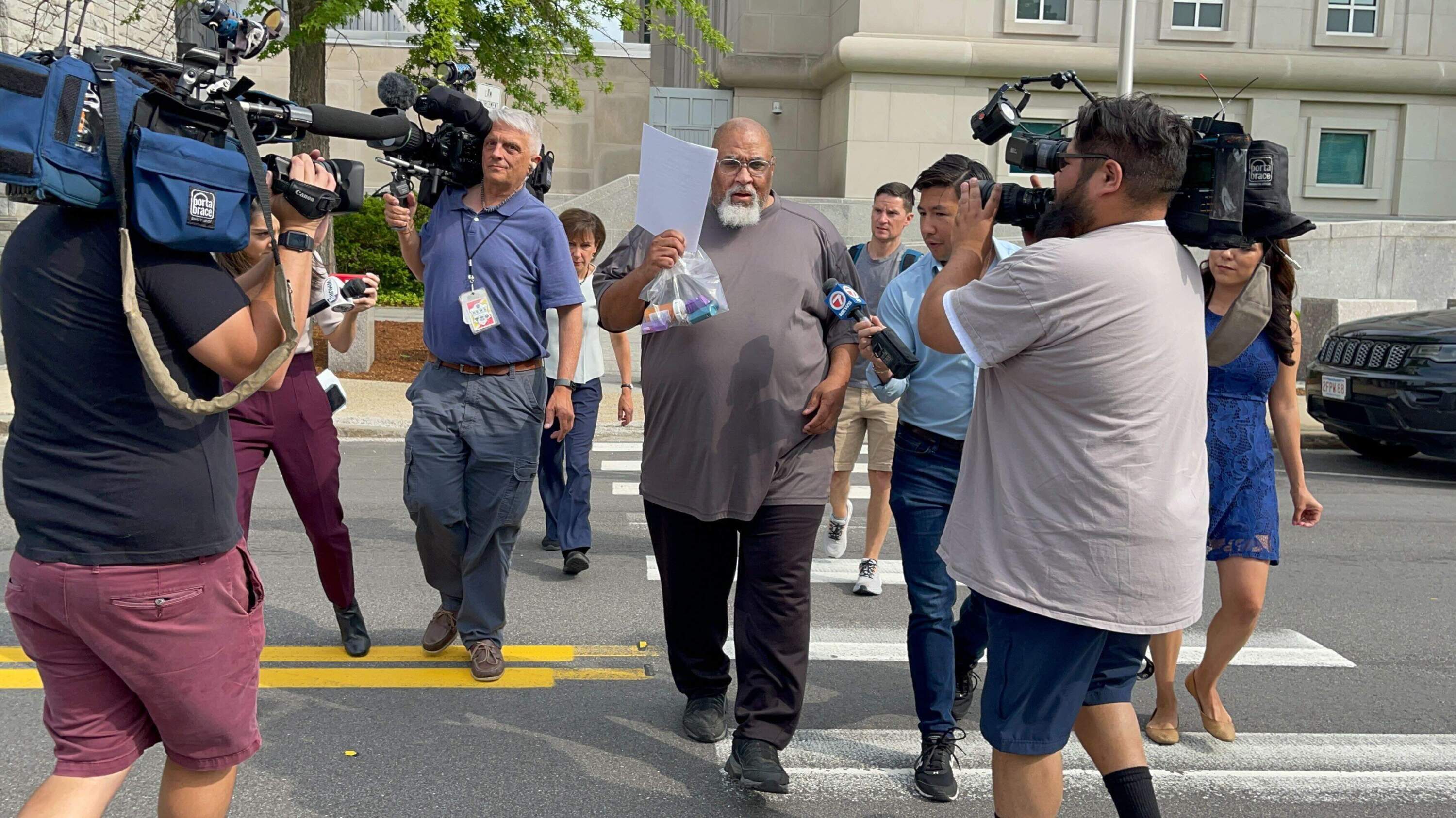 Former Harvard Medical School morgue manager Cedric Lodge, 55, shields his face with a printout of the indictment against him as he walked from the Warren B. Rudman United States Courthouse in Concord, New Hampshire, following his arrest on charges related to an alleged scheme to steal and sell donated body parts. (Steven Porter/The Boston Globe via Getty Images)