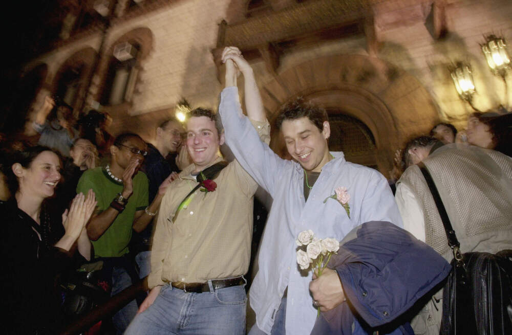 A gay couple clasp hands in response to applause from a large crowd as they emerge from City Hall after applying for a marriage license in the early hours of May 17, 2004 in Cambridge, Mass. Cambridge City Hall opened its doors before midnight to become the first city in Mass. to issue licenses for same sex marriages. (Michael Springer/Getty Images)