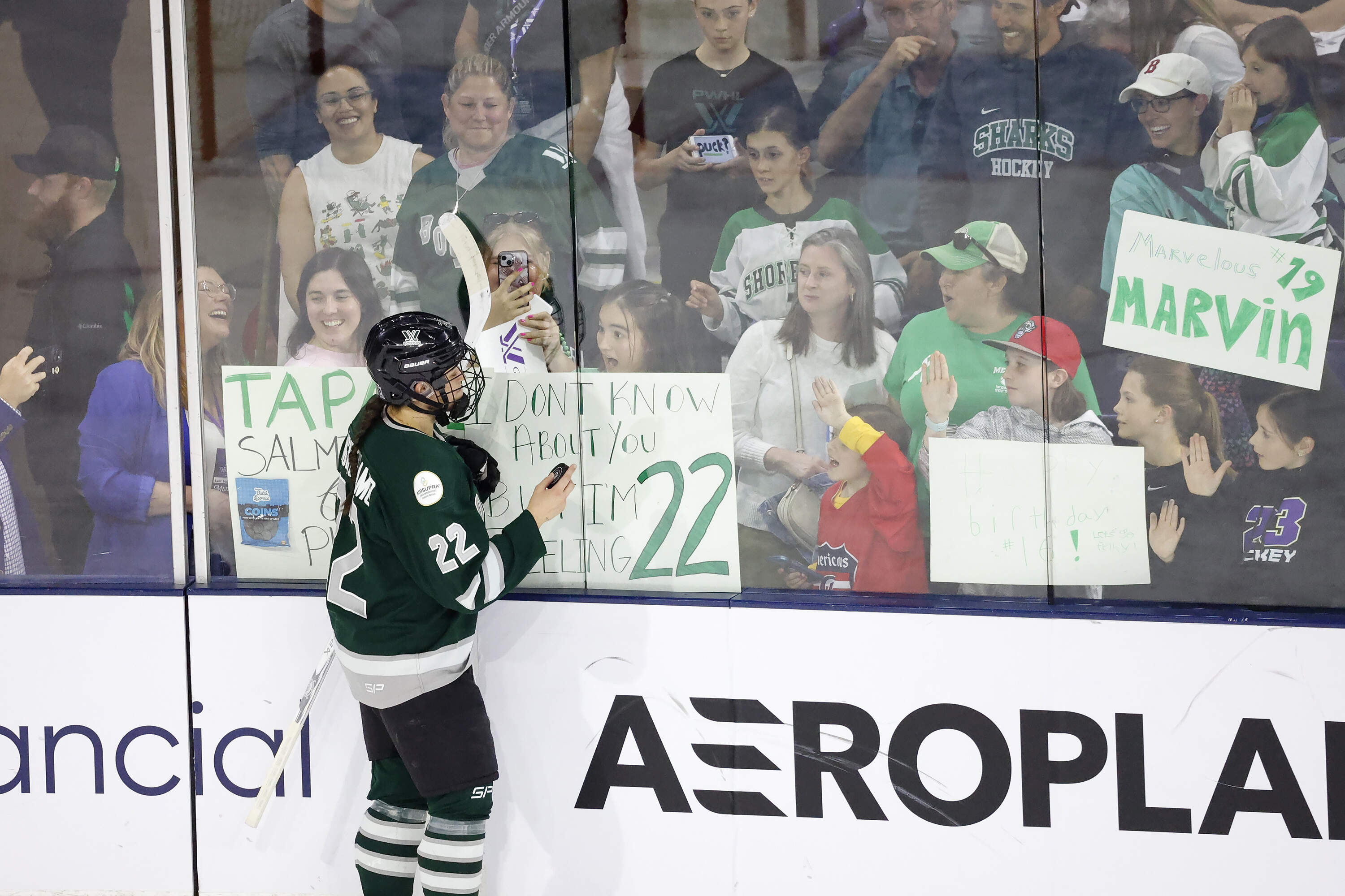 A young fan reacts at the glass as Boston defender Jessica Digirolamo (22) talks to her before tossing her a puck before the start of Game 5 of the PWHL Walter Cup hockey finals. (Mary Schwalm/AP)