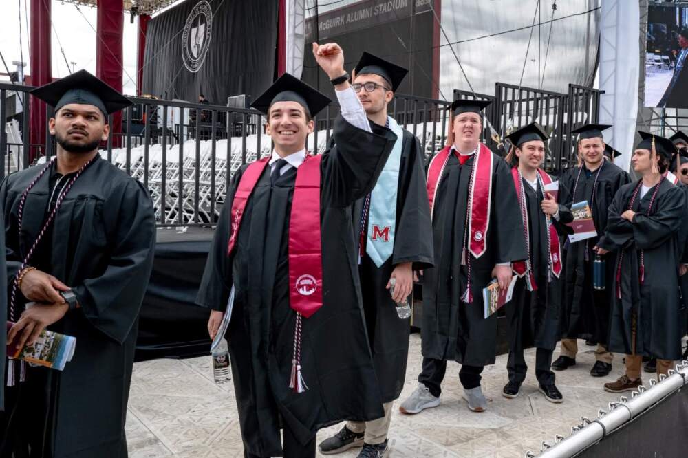 A graduating senior waves to family members as he enters McGuirk Stadium for the UMass Amherst commencement ceremony on May 18, 2024. (Ben James/NEPM)