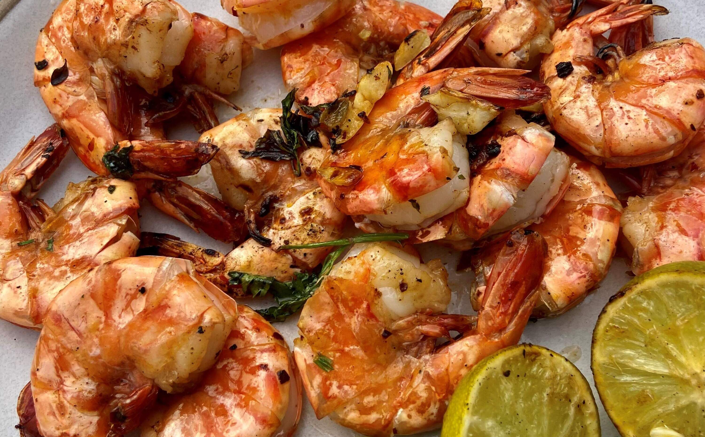 Grilled shrimp with green cilantro-chile-lime sauce and grilled limes. (Kathy Gunst/Here & Now)