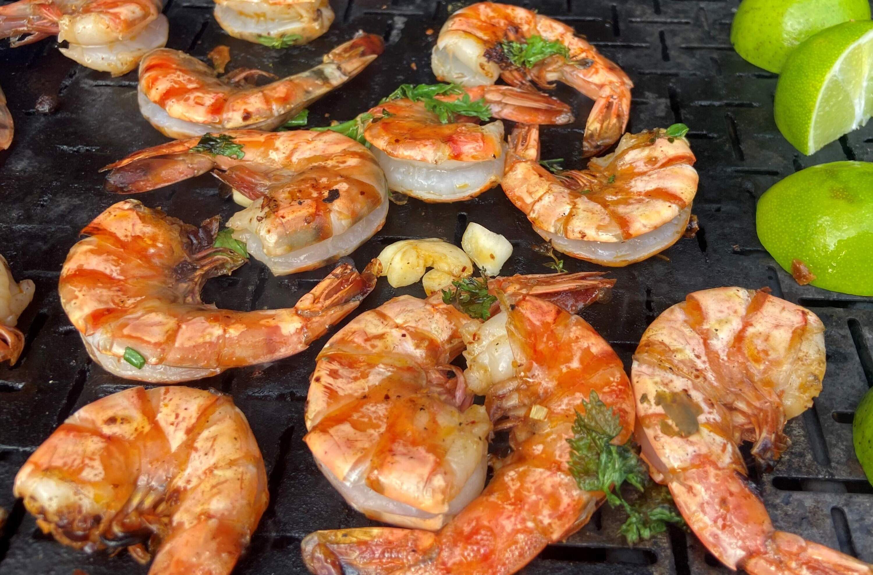 Grilled shrimp with green cilantro-chile-lime sauce and grilled limes. (Kathy Gunst/Here &amp; Now)