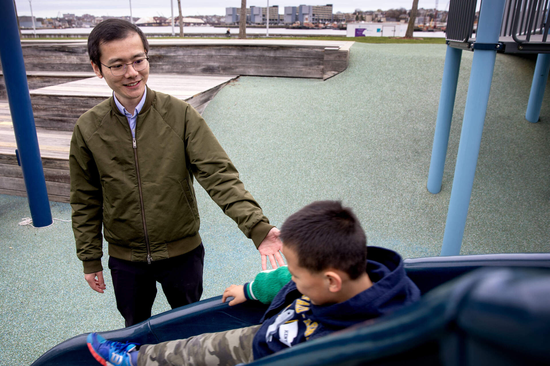 Yang Cao watches as his son Zhentao plays on a slide at Menino Park in Charlestown. (Robin Lubbock/WBUR)