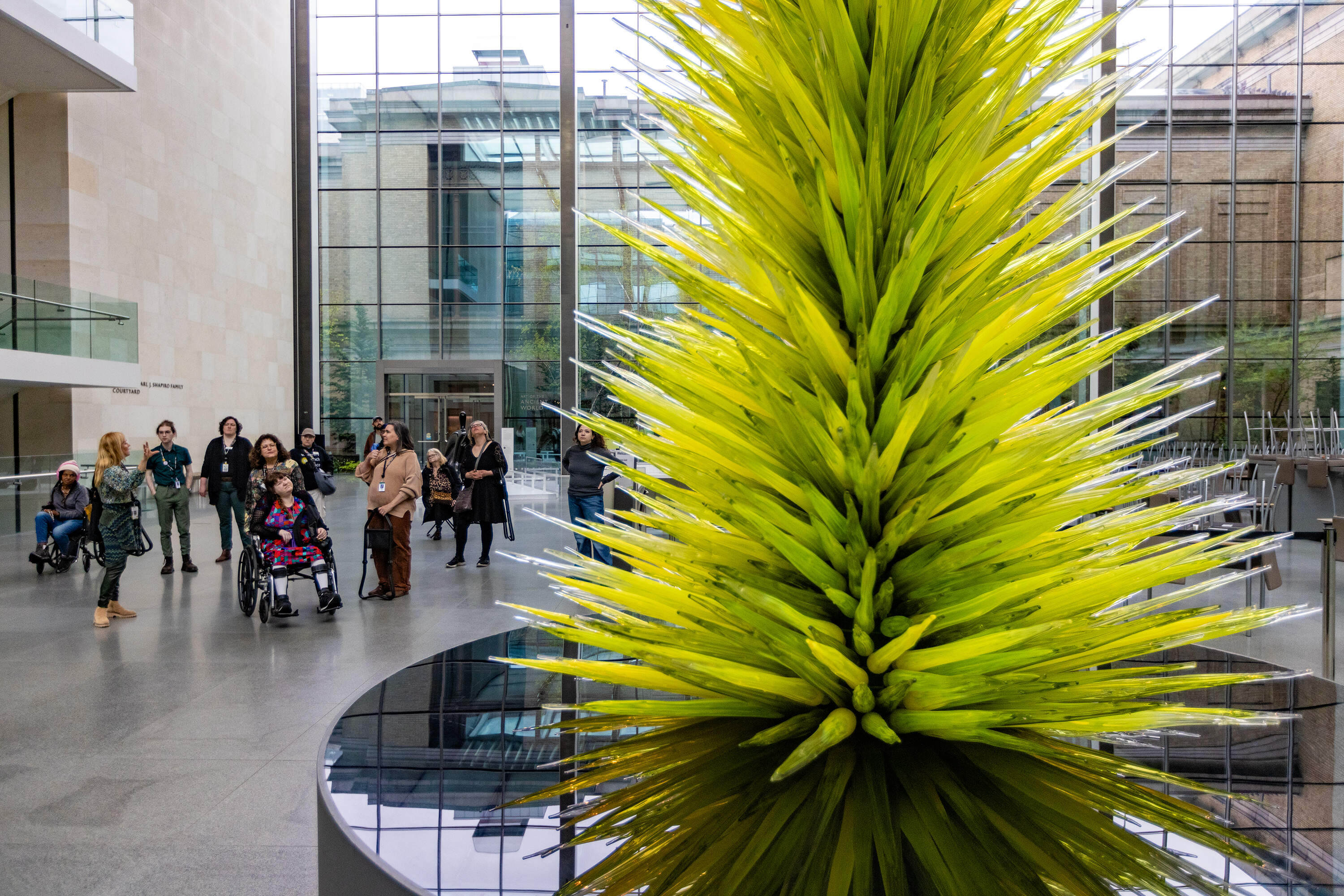 The women on the tour look at Dale Chihuly’s Lime Green Icicle Tower. (Jesse Costa/WBUR)
