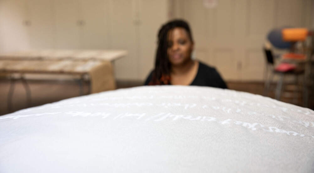 Phrases in white, written across a muslin background in &quot;Mother Tongue&quot; by artist Tanya Nixon-Silberg. (Robin Lubbock/WBUR)