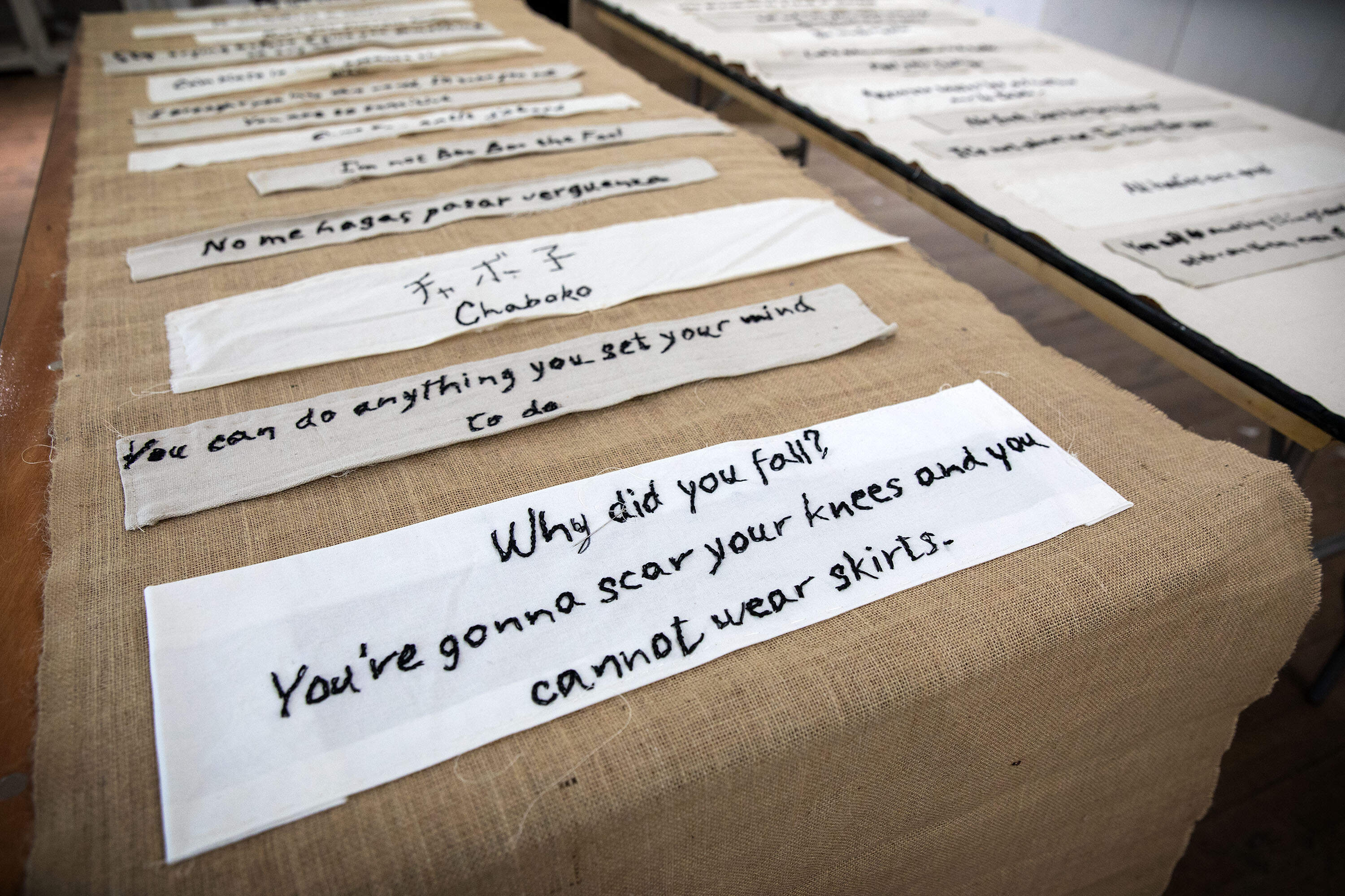 Artist Tanya Nixon-Silberg's "Mother Tongue" shows phrases heard in childhood on a burlap background, and phrases heard today on a muslin background. (Robin Lubbock/WBUR)