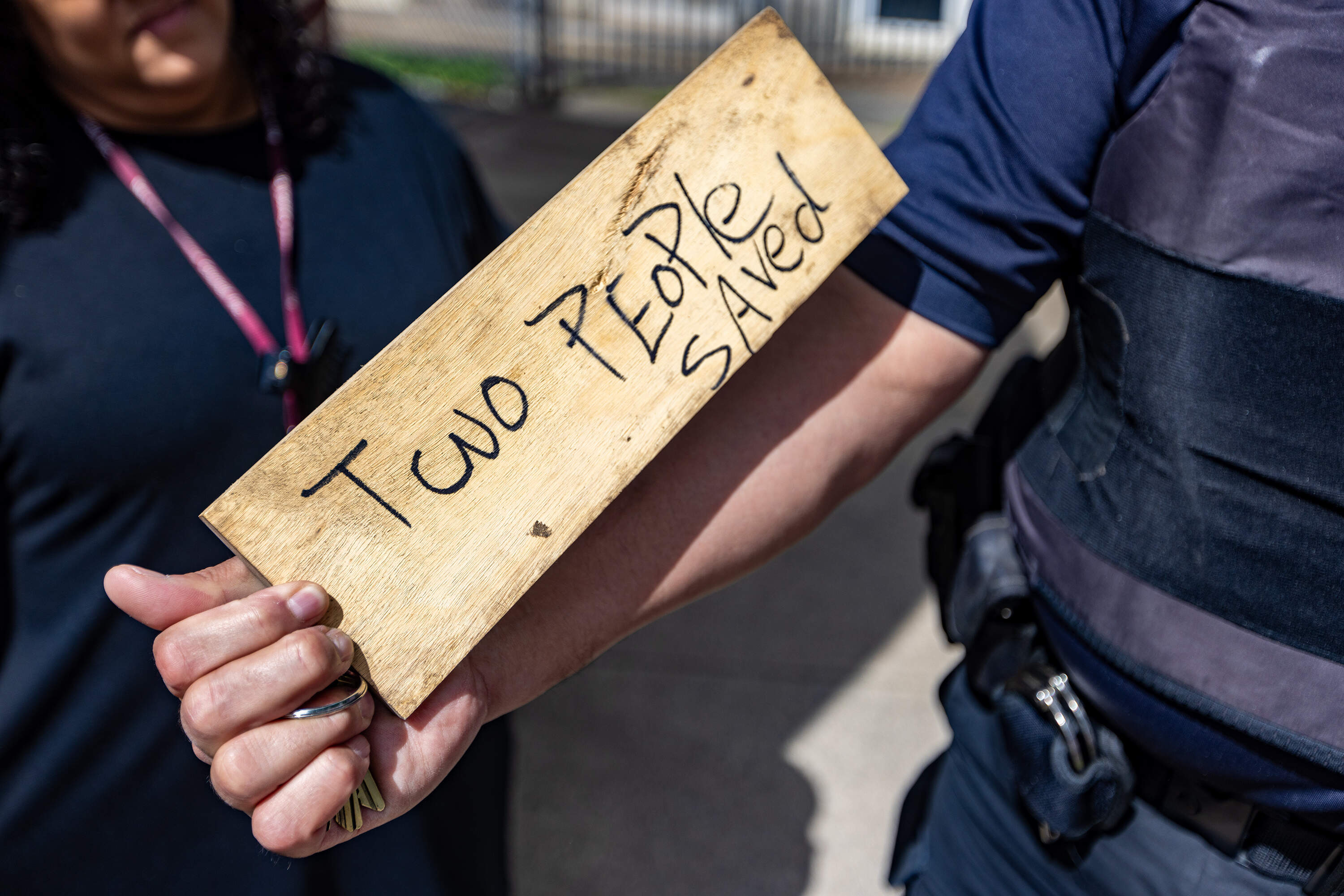 Security Supervisor for the Hampden County Sheriff's Office, Dan Cruz, holds a sign someone left on top of the NaloxBox Opioid Rescue Kit mounted to the front wall of a Sheriff’s Office building. (Jesse Costa/WBUR)