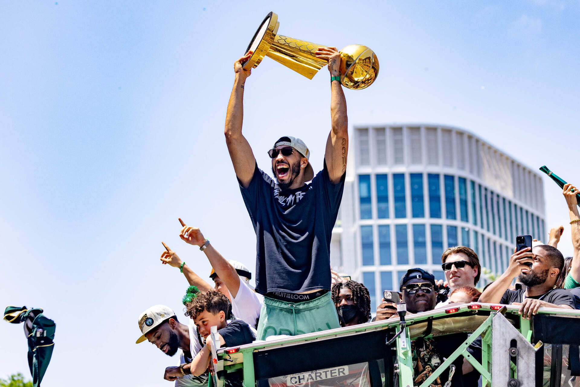 Jayson Tatum hoists the NBA Finals trophy during the Celtics championship parade in Boston. (Jesse Costa/WBUR)