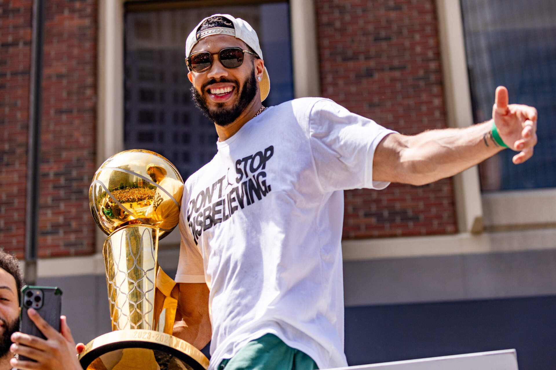 Jayson Tatum holds the NBA Finals trophy while he celebrates with fans during the Celtics championship parade in Boston. (Jesse Costa/WBUR)