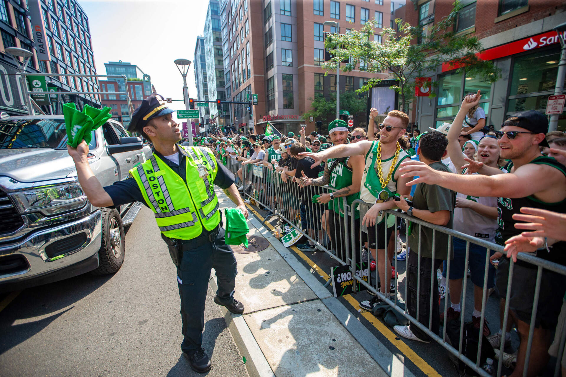 A Boston Police officer tosses Celtics towels out to the crowd waiting outside of TD Garden prior to the rolling rally. (Jesse Costa/WBUR)