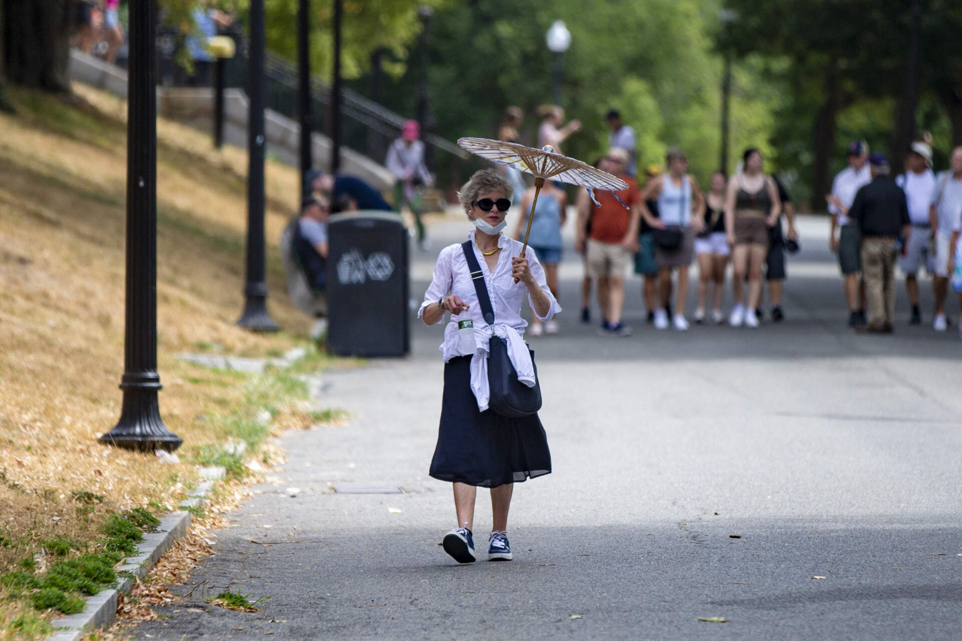 A woman walks with an umbrella shielding herself from the sun in Boston Common. (Jesse Costa/WBUR file photo)