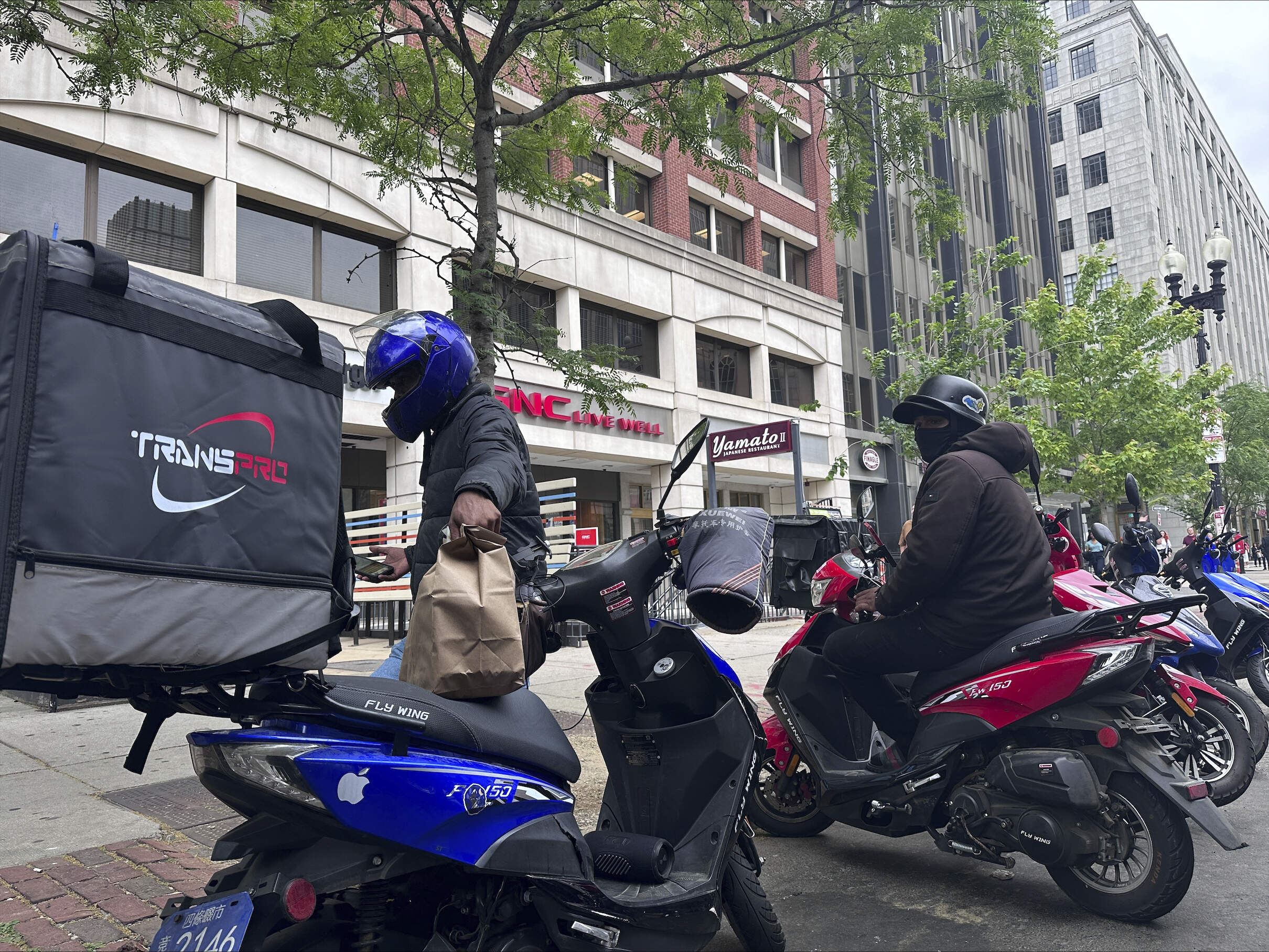 Delivery scooters are parked as drivers wait to pick up food for delivery, Thursday, June 6, 2024, in Boston. (Michael Casey/AP)