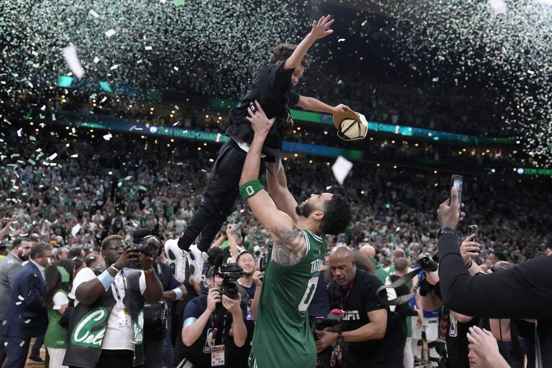 Boston Celtics forward Jayson Tatum lifts his son Deuce as he celebrates with the team after the Celtics won the NBA championship with a Game 5 victory over Dallas Mavericks. (Charles Krupa/AP)