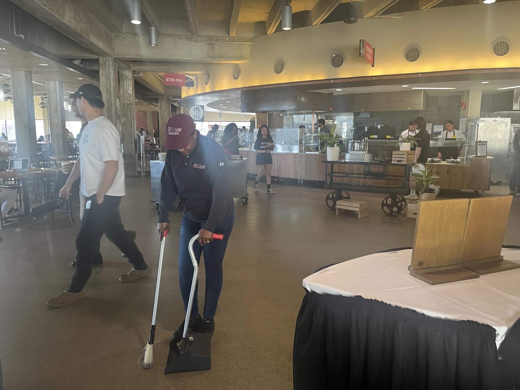 Emma, a Haitian migrant staying at the state shelter in Greenfield, Massachusetts, cleans a dining room at UMass Amherst after receiving her federal work authorization. (Nirvani Williams/NEPM)