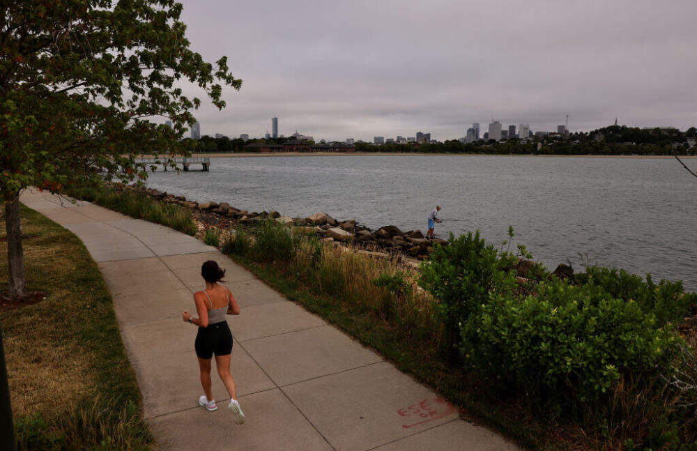 A woman jogs on the Harborwalk that runs along the former Bayside Expo Center property in Boston, MA on June 21, 2022. (Craig F. Walker/The Boston Globe via Getty Images)