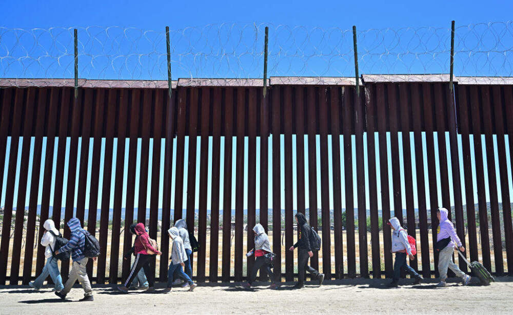 Migrants walk on the US side of the border wall in Jacumba Hot Springs, California on June 5, 2024, after crossing from Mexico. (FREDERIC J. BROWN/AFP via Getty Images)