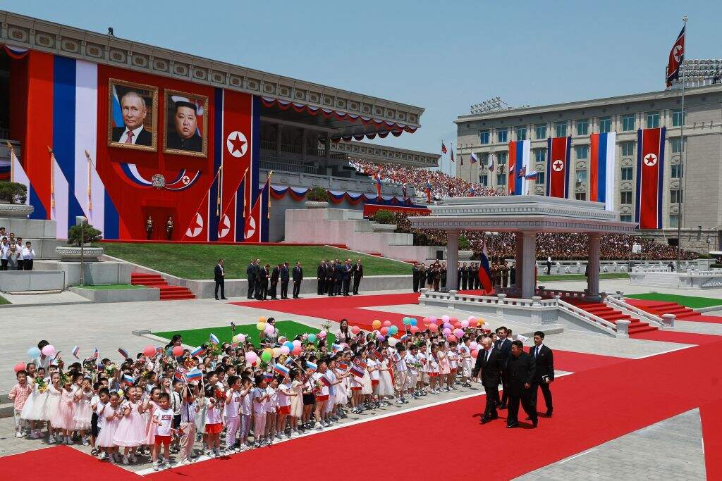 TOPSHOT - In this pool photograph distributed by the Russian state agency Sputnik, North Korea's leader Kim Jong Un (Center-R) and Russian President Vladimir Putin (L) walk past children attend a welcoming ceremony at Kim Il Sung Square in Pyongyang on June 19, 2024. Russian President Vladimir Putin landed in North Korea early on June 19, the Kremlin said, kicking off a visit set to boost defence ties between the two nuclear-armed countries as Moscow pursues its war in Ukraine. (Photo by Vladimir SMIRNOV / POOL / AFP) / -- Editor's note : this image is distributed by the Russian state owned agency Sputnik -- (Photo by VLADIMIR SMIRNOV/POOL/AFP via Getty Images)