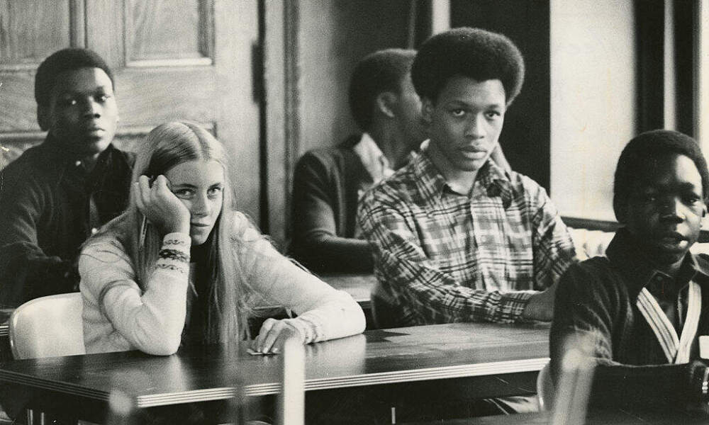 Eileen Dunner, of Uphams Corner in Dorchester, left, sits in Room 610 on her first day at Roxbury High School on Sept. 12, 1974. (Tom Landers/The Boston Globe via Getty Images)
