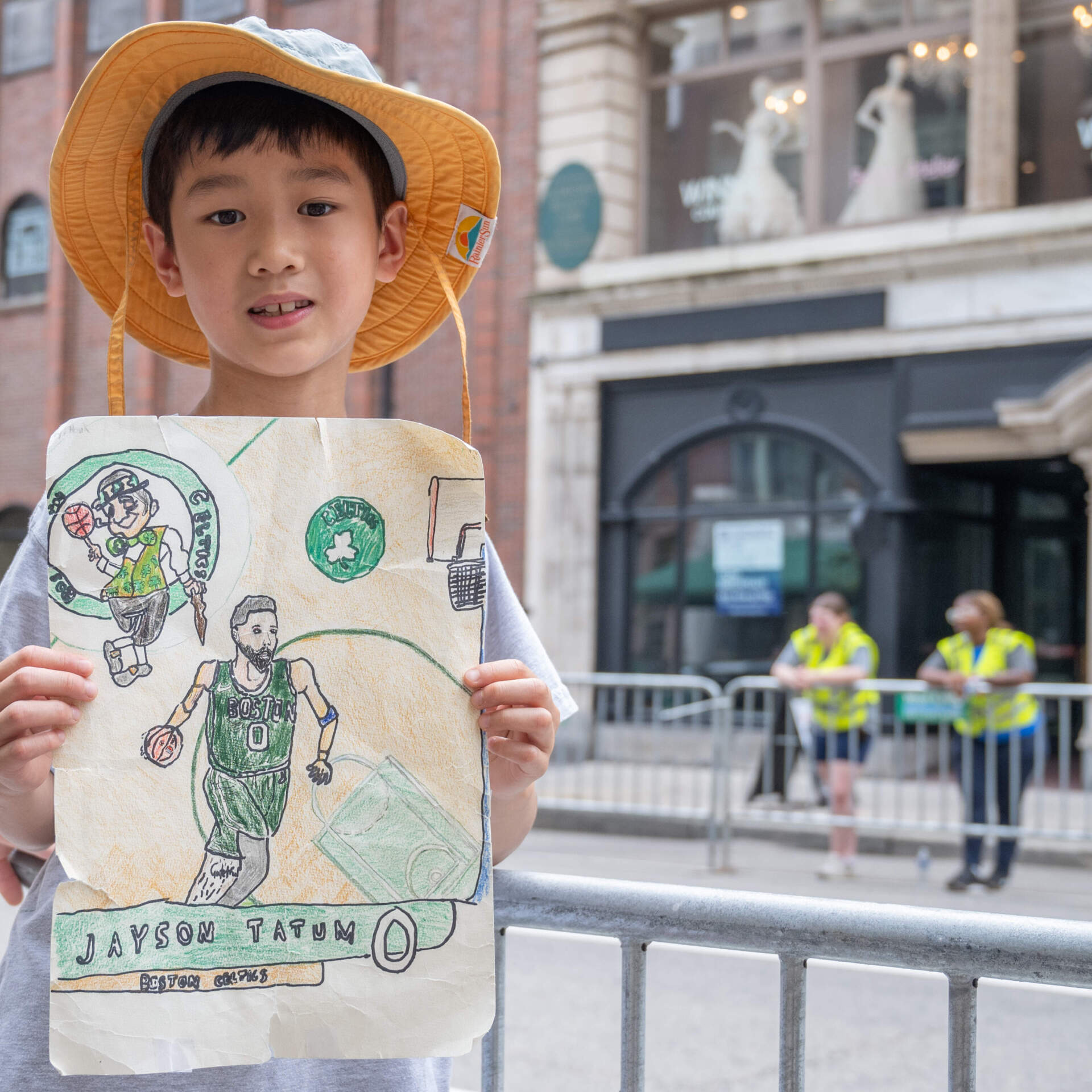 Waiting for the parade on Boylston Street, 8-year-old Hank Li of Brookline displays the poster he drew featuring his favorite player, Jayson Tatum. (Sharon Brody/WBUR)