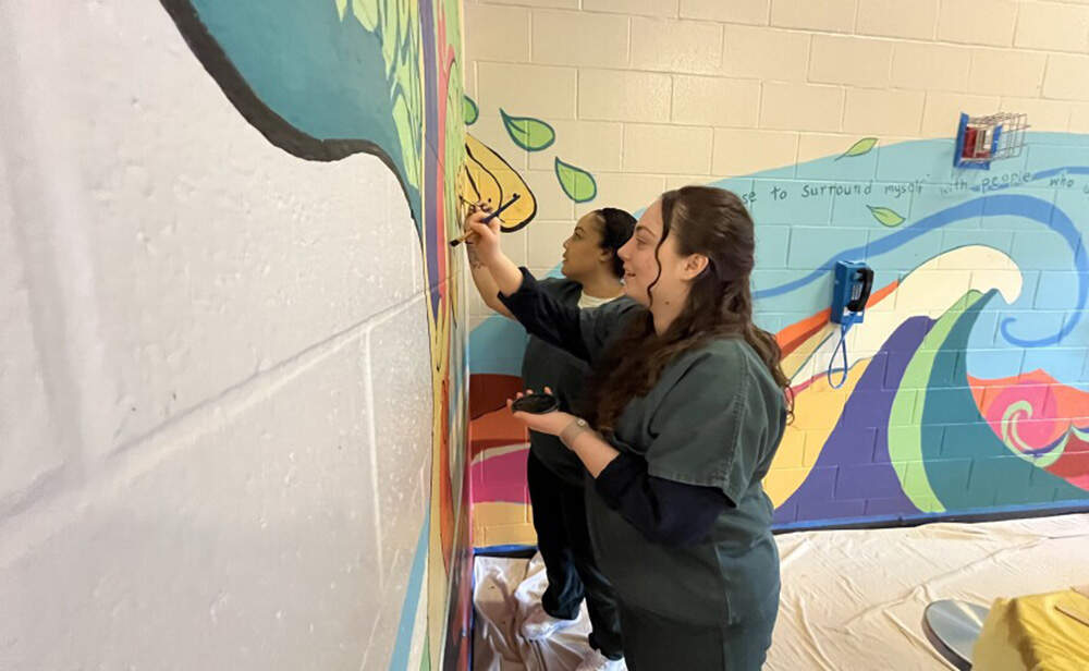 Tianna and Jessica paint a mural on the cinderblock walls. (Patrick Flanary/CAI)