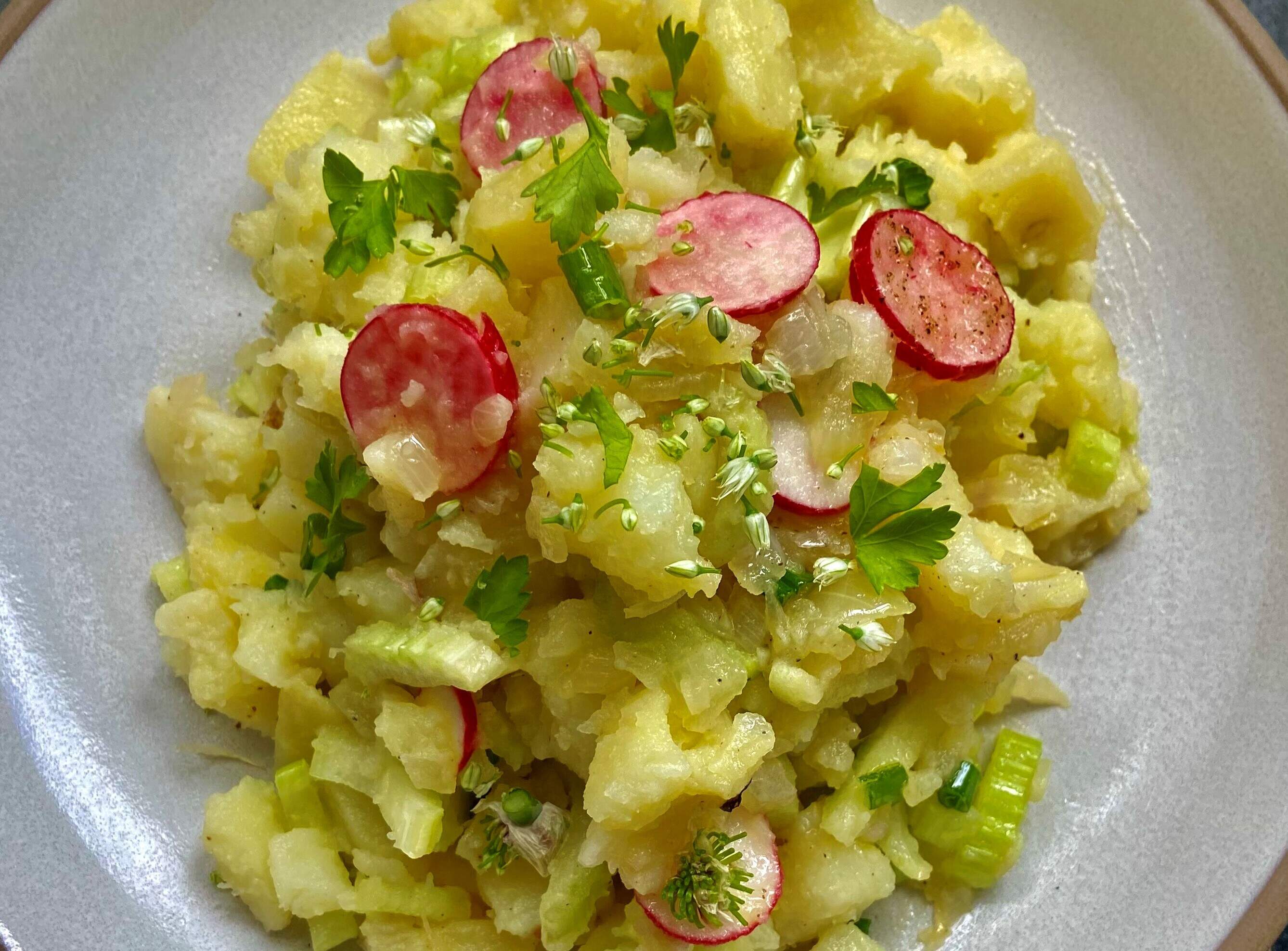 Summer potato salad with sauteed onions, radishes and herbs. (Kathy Gunst/Here &amp; Now)