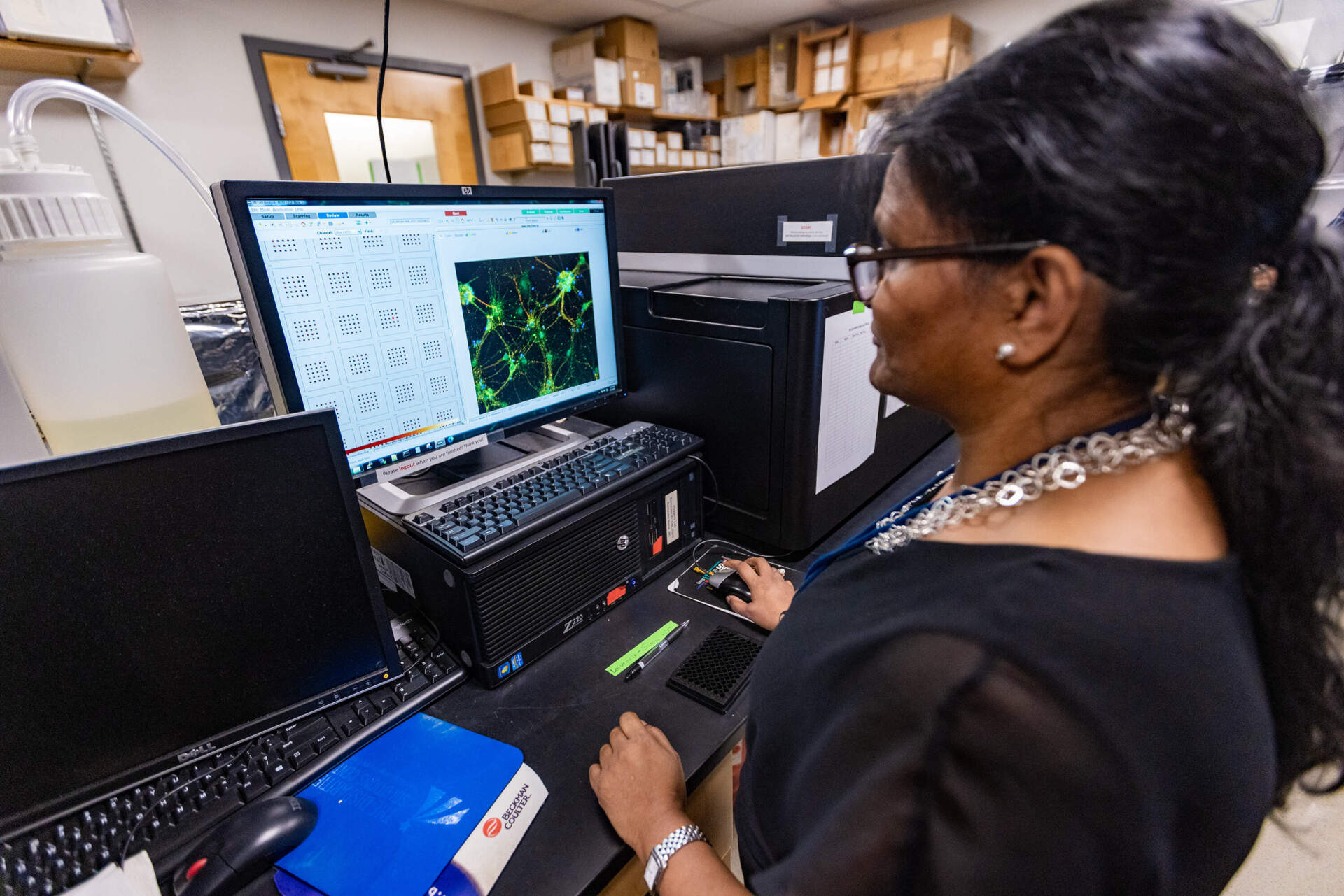 Surya Reis, executive director of the medicinal plant laboratory at Massachusetts General Hospital, looks at brain cells that were created from stem cells using the InCell Analyzer 6000 microscope. This helps researchers study how neurons react to psychoactive compounds. (Jesse Costa/WBUR)