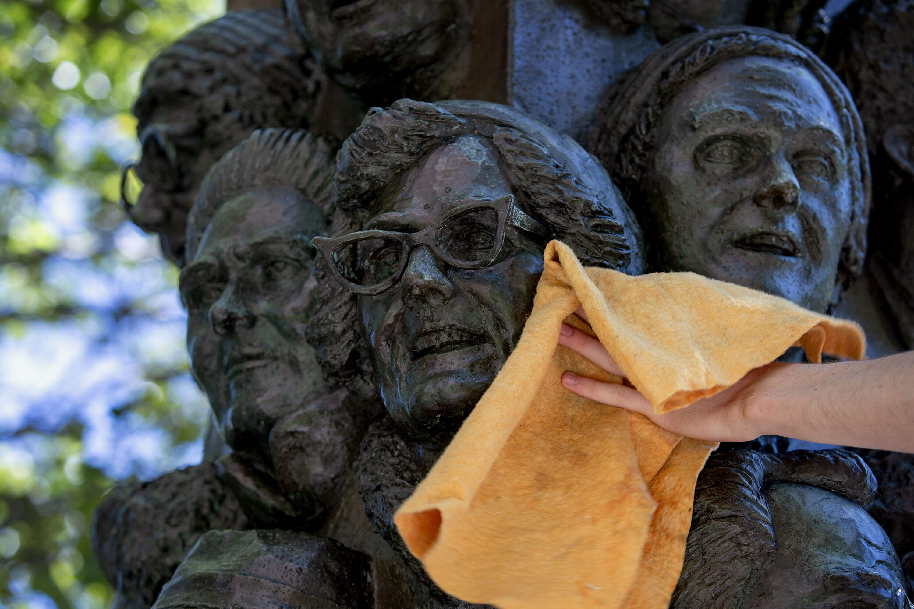 Faces on sculptor James Tyler's "Tower of East Cambridge Faces" get dried, as part of a routine cleaning by Cambridge Arts conservation technicians. (Robin Lubbock/WBUR)