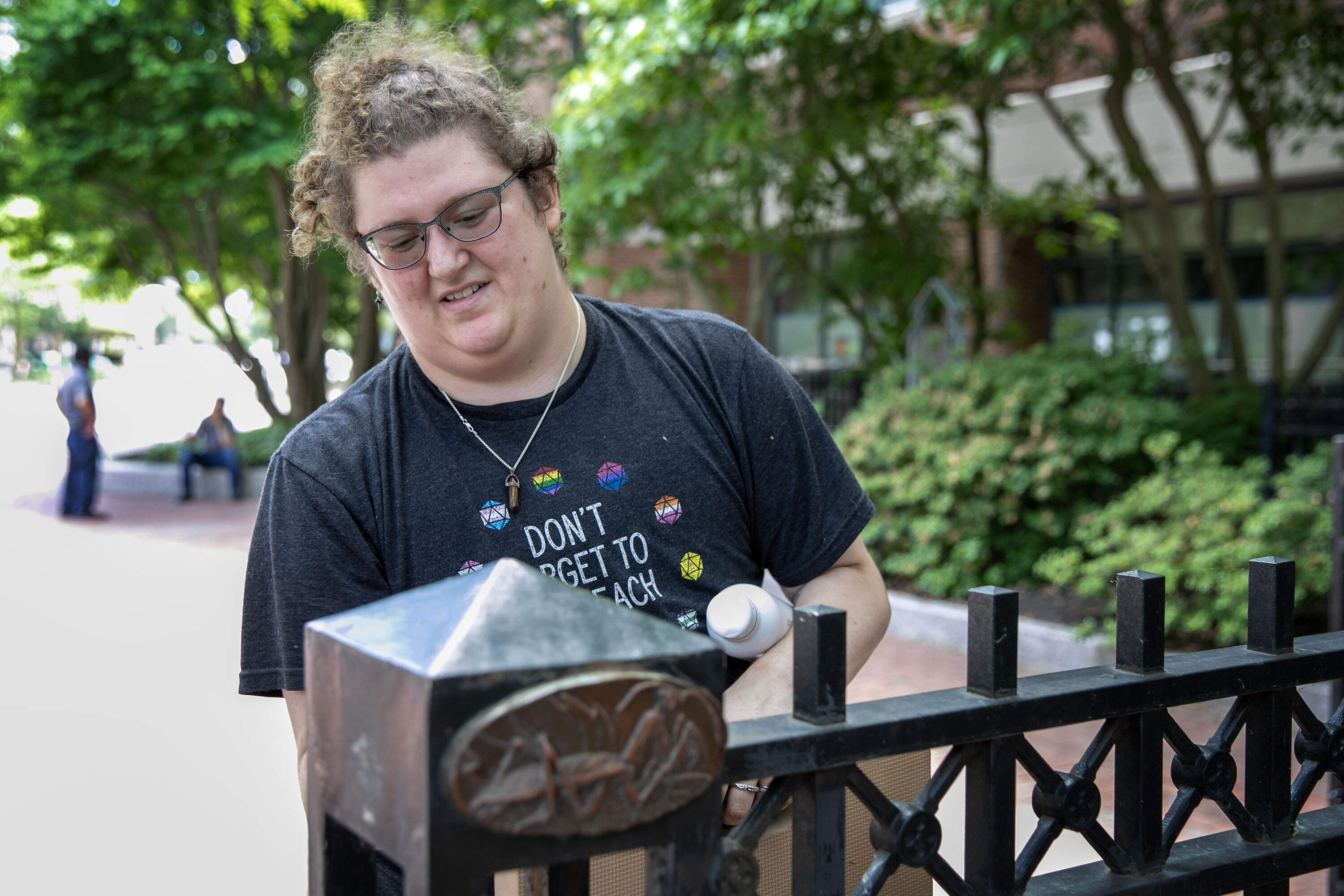 Cambridge conservation technician Alyx Zavetnya works on an insect medallion sculpture by Nancy Webb at the entrance to Charles Park. (Robin Lubbock/WBUR)