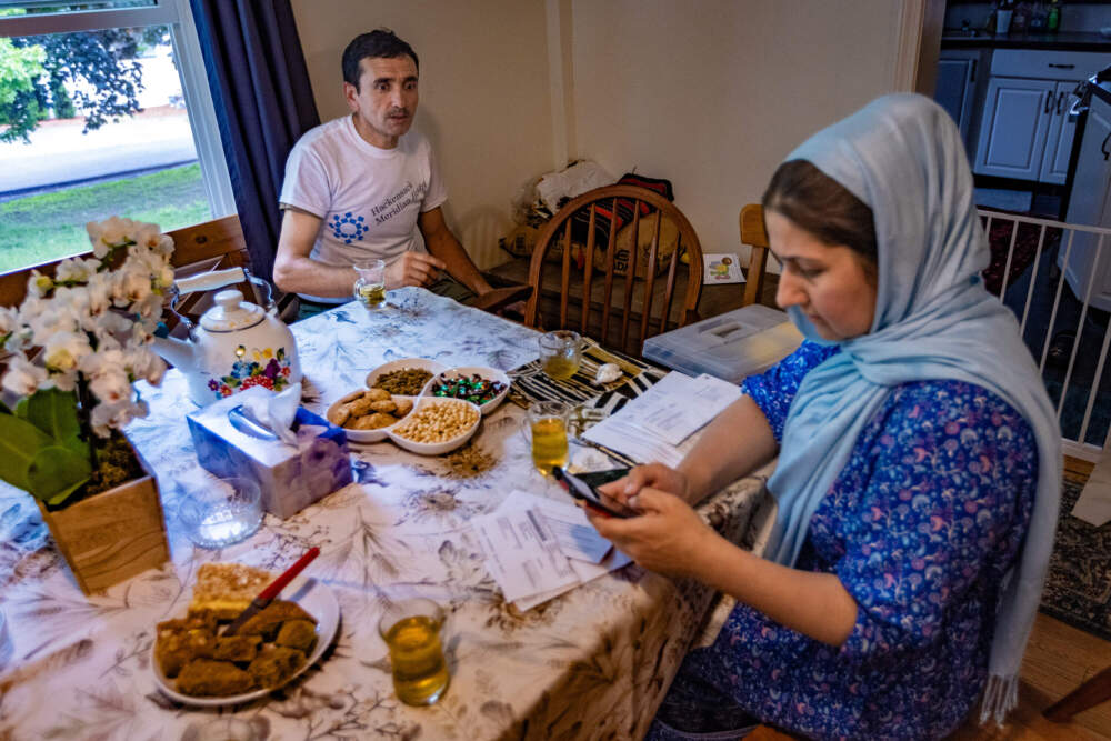 Patmana Rafiq-Kunary, of the New American Association of Massachusetts, helps Sami access his bank account with the online app on his phone. (Jesse Costa/WBUR)