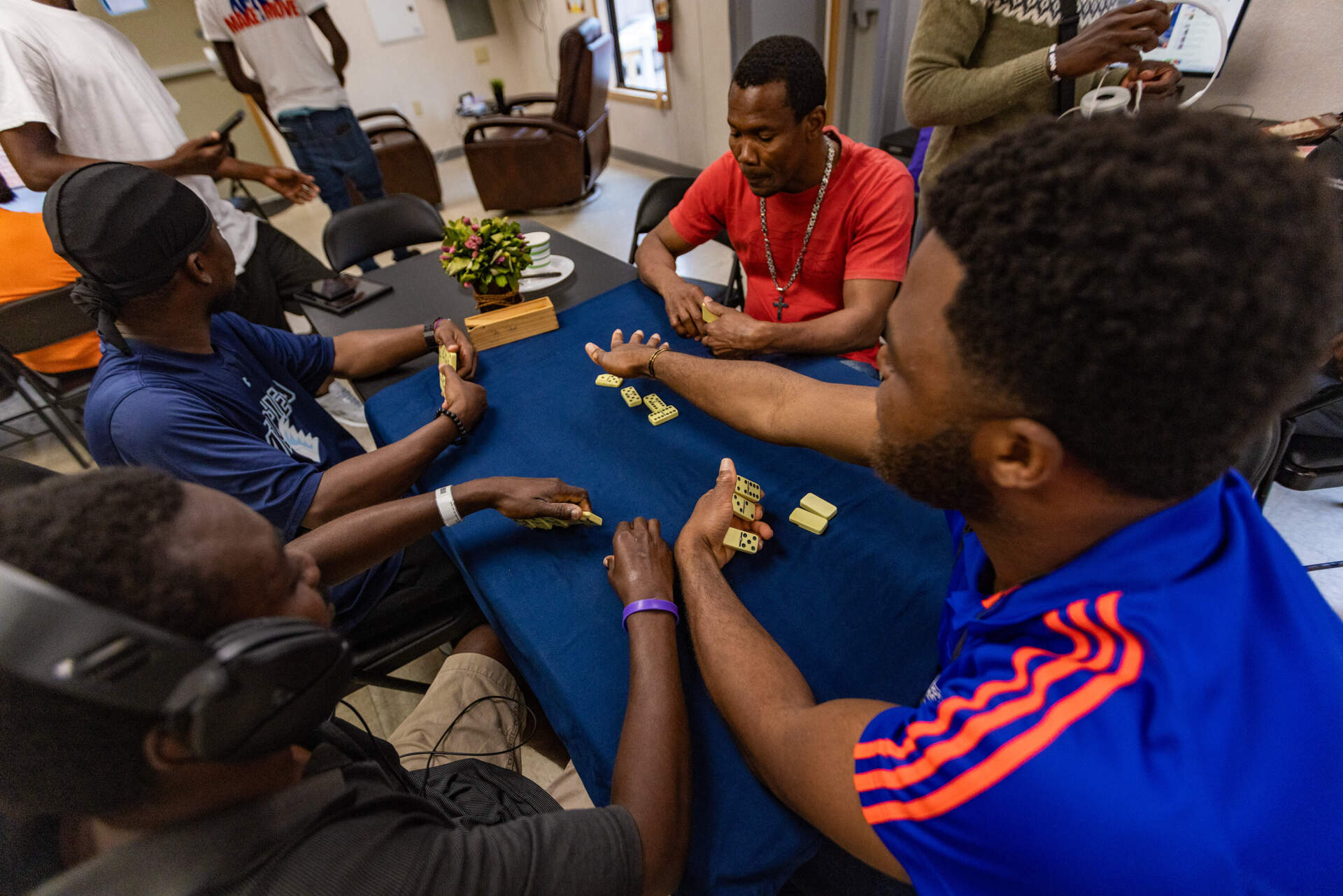 A group of Haitian men play dominoes to pass the time. The Whittier Street Health Center operates a day center, which lately is populated by migrants who recently arrived in the state. (Jesse Costa/WBUR)