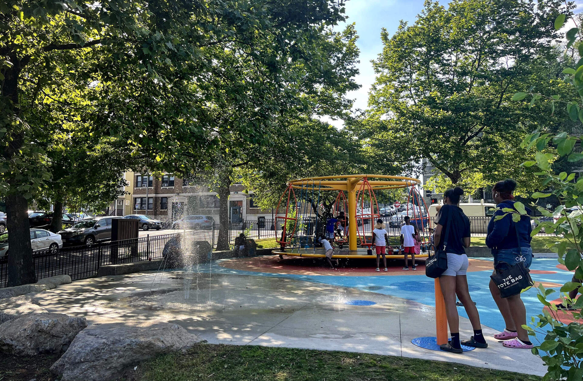 Families attempt to stay cool on a recent sunny day at the Walker Playground splash pad in Mattapan. The nearest city-run pool in the neighborhood is closed for repairs. (Amy Sokolow/WBUR)