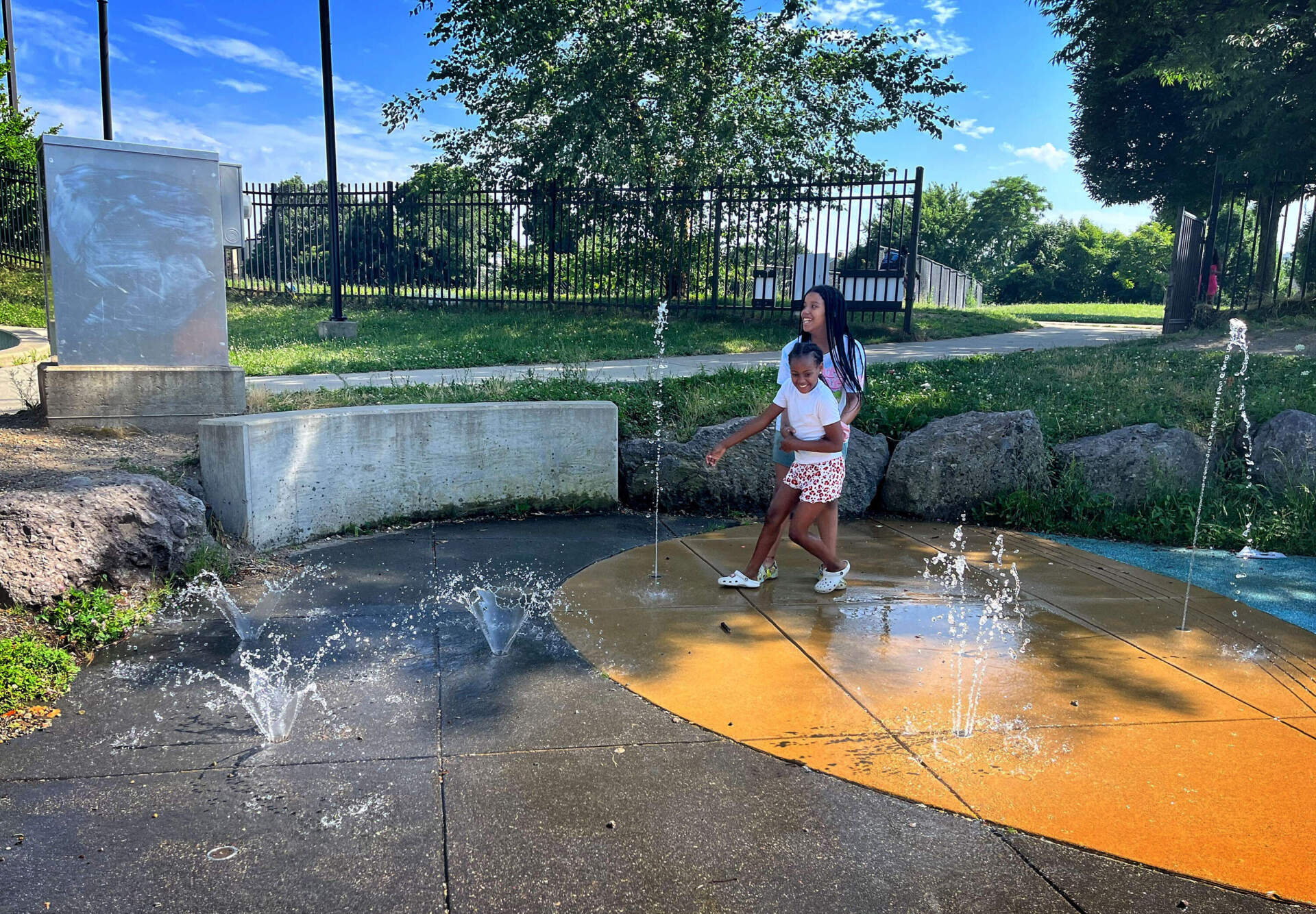 Young people enjoy a splash pad playground in Dorchester. The nearby indoor Holland Pool is closed. (Robin Lubbock/WBUR)