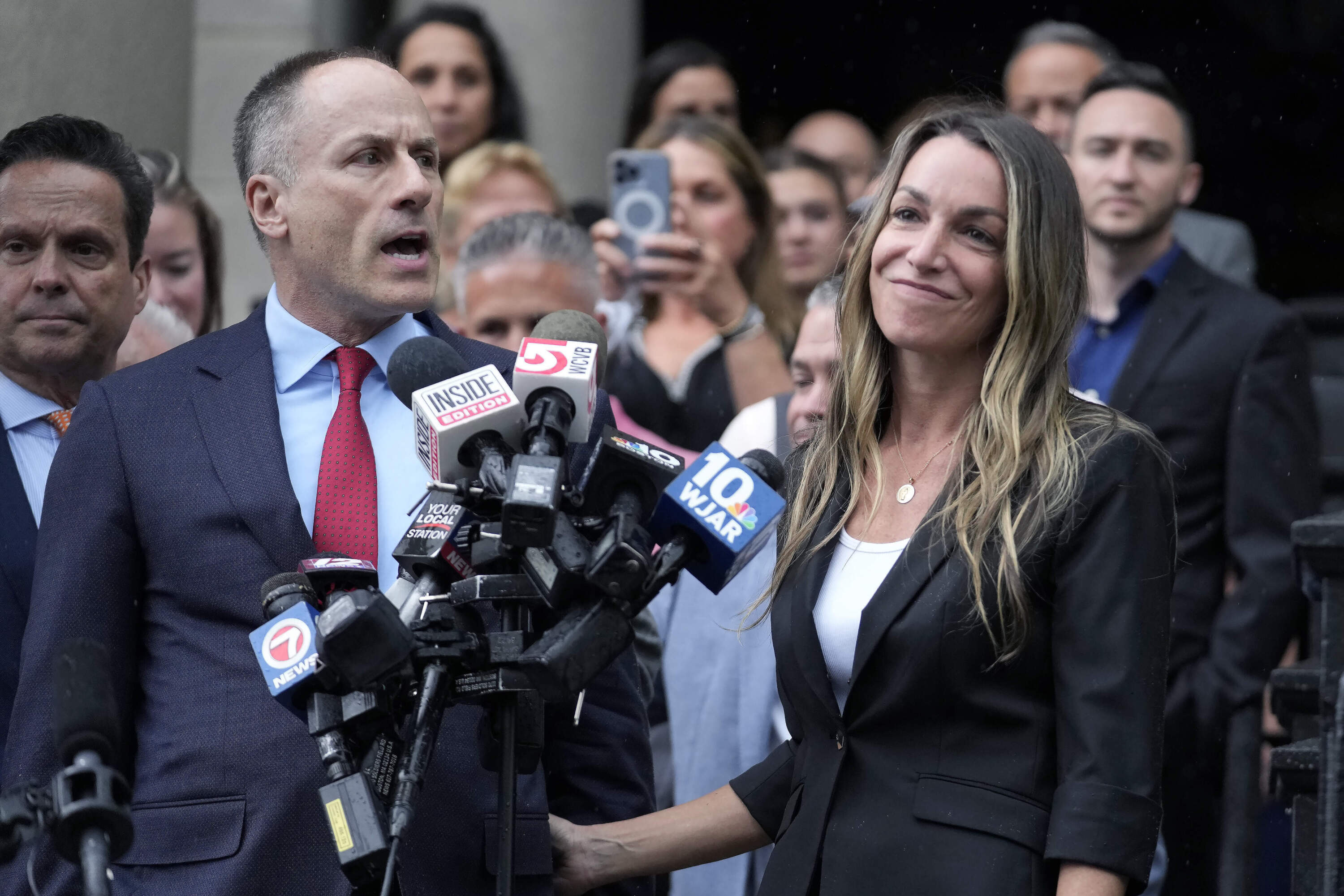 Karen Read, right, smiles as defense attorney David Yannetti, front left, speaks to reporters in front of Norfolk Superior Court after the judge declared a mistrial after jurors were unable to reach a verdict following a two-month trial on Monday, July 1. (Steven Senne/AP)