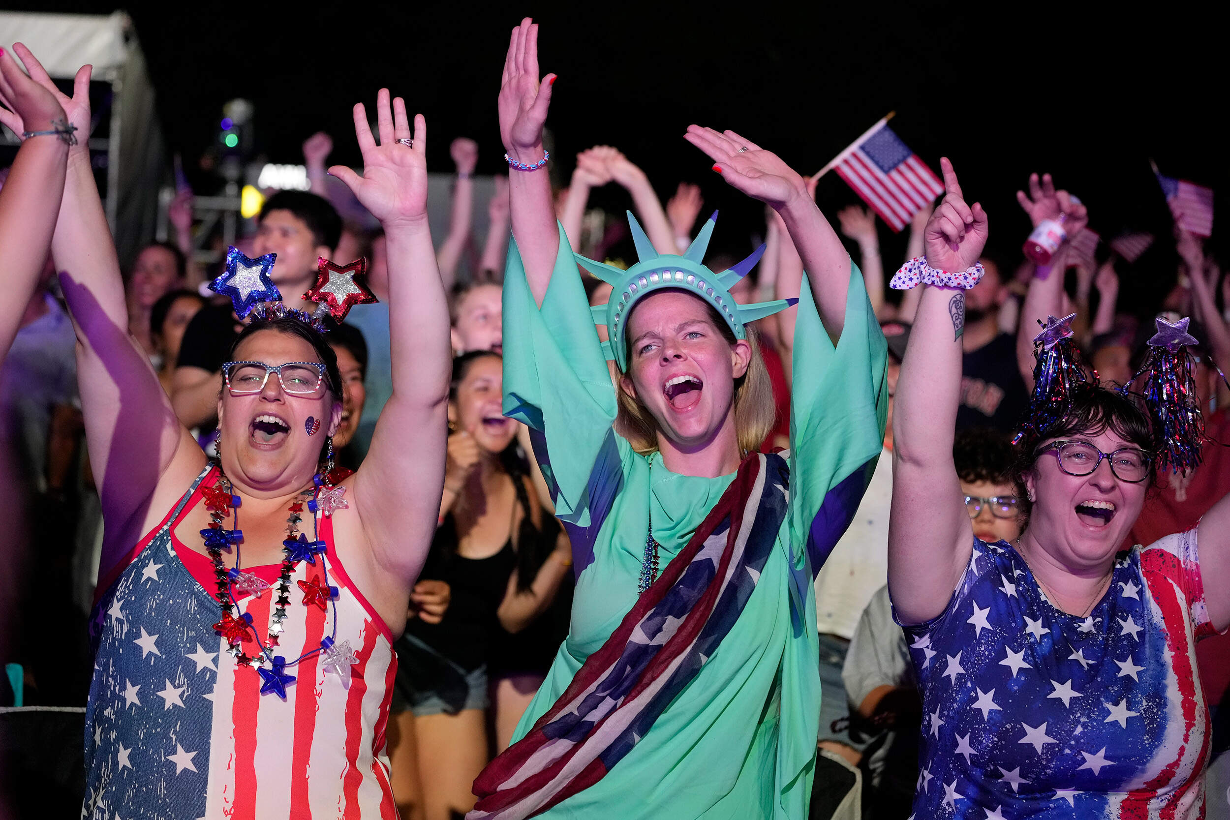 Meagan Rebelo left, Jackie Washburn, center, and Lauren Thompkins, right, celebrate during the Boston Pops Fireworks Spectacular. (Michael Dwyer/AP)