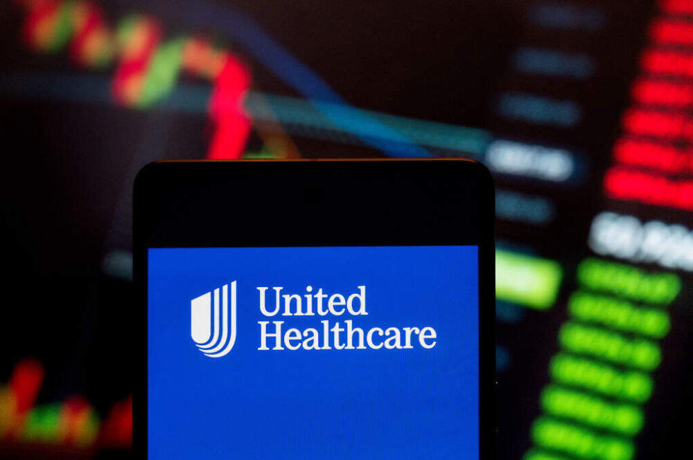 In this photo illustration, the American multinational managed healthcare and insurance company UnitedHealth Group (NYSE: UNH) logo seen displayed on a smartphone with an economic stock exchange index graph in the background. (Budrul Chukrut/SOPA Images/LightRocket via Getty Images)