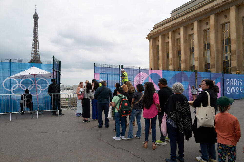 Tourists line up to catch a glimpse of the Eiffel Tower and take photos through a gap in the fence on July 2 as Trocadéro Square in Paris is temporarily closed due to preparations for the Olympics. (Pierre Crom/Getty Images)