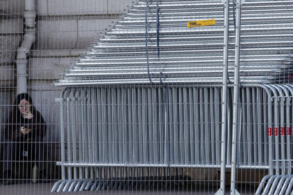 A woman smokes a cigarette next to barriers stored on a sidewalk in Paris on July 4, in preparation for the opening ceremony of the Paris 2024 Olympics. (Joel Saget/AFP via Getty Images)