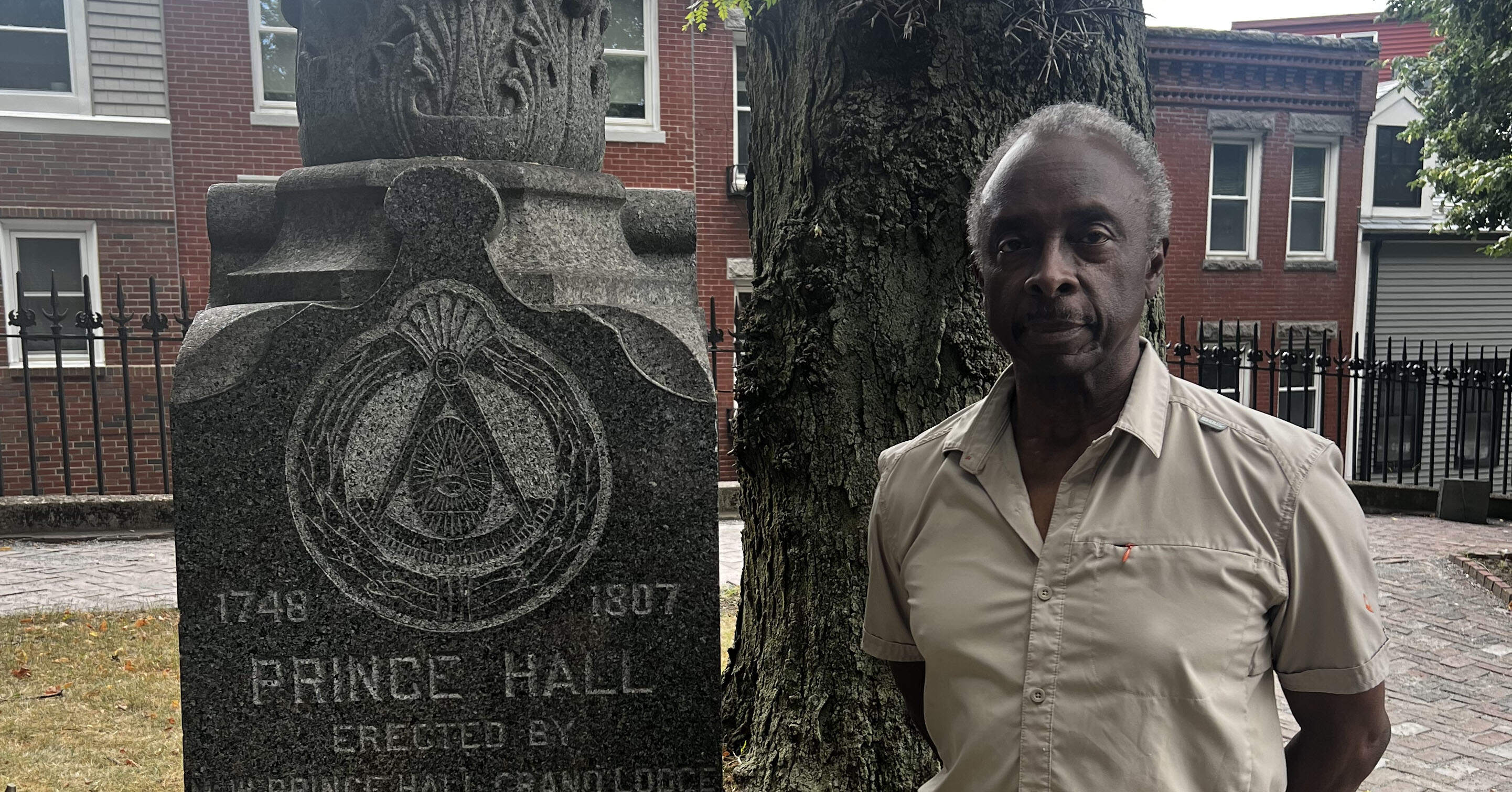 Roberto Mighty stands beside a monument to Prince Hall, a prominent black leader and abolitionist of the time, inside the North End’s Copp’s Hill Burying Ground. (Cristela Guerra/WBUR)