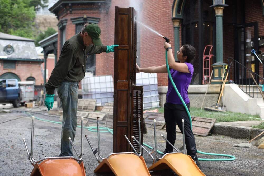 Volunteer Sophie Feldman and building owner Vince Illuzzi clean furniture outside on Sunday, July 16, 2023. (Mike Dougherty/Vermont Public)