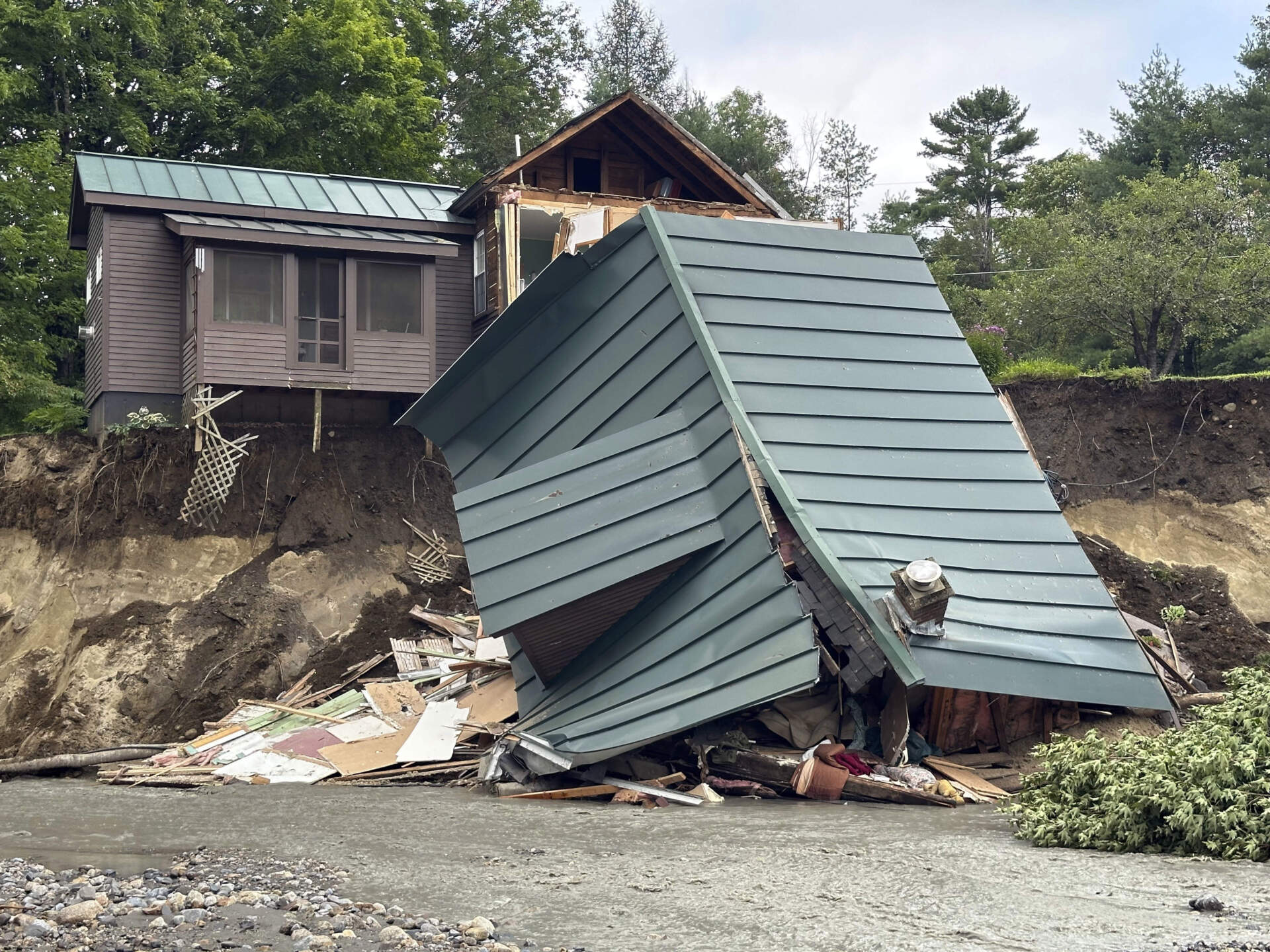 Trees and debris sit next to a damaged home after flooding in Lyndonville, Vt. (Nick Perry/AP)