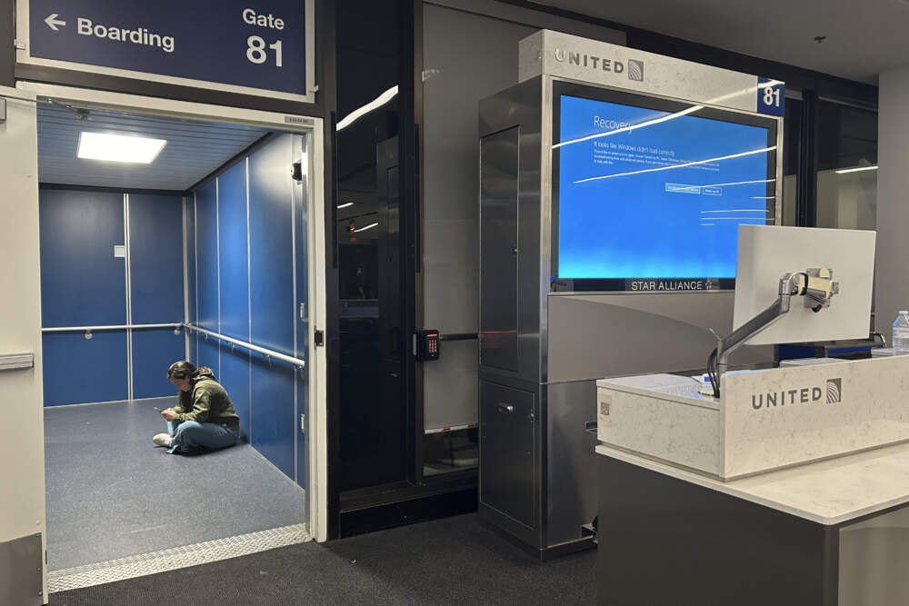 A traveler at Los Angeles International Airport sits in a jetway for a delayed United Airlines flight to Dulles International Airport due to a widespread global technology outage disrupting flights, banks media outlets and companies around the world, Friday, July 19, 2024. (Stefanie Dazio/AP)