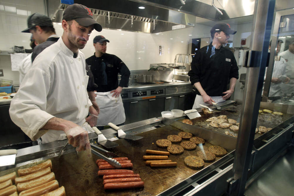 Aramark employees grill hot dogs, hamburgers and chicken at the concession area behind home plate at Fenway Park in Boston in March 2010. (Elise Amendola/AP)