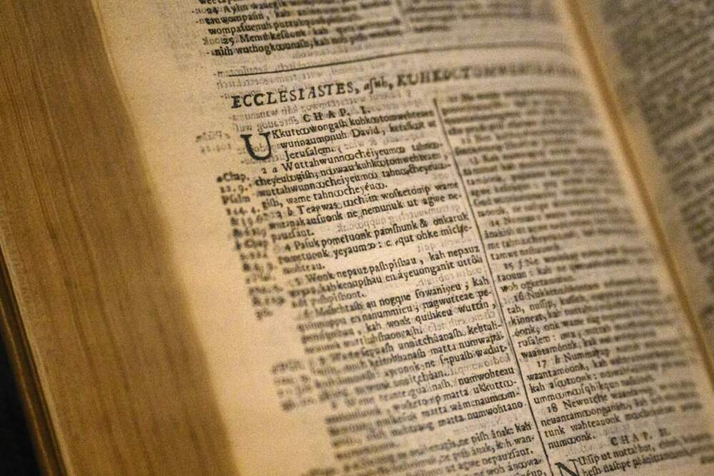 The first translation of a Christian Bible into an Indigenous language sits in a display in the “Entwined” exhibition at the Mystic Seaport Museum. The Bible was translated to an Algonquian language by English Puritan John Eliot with the assistance of several Native scholars. (Ryan Caron King/Connecticut Public)