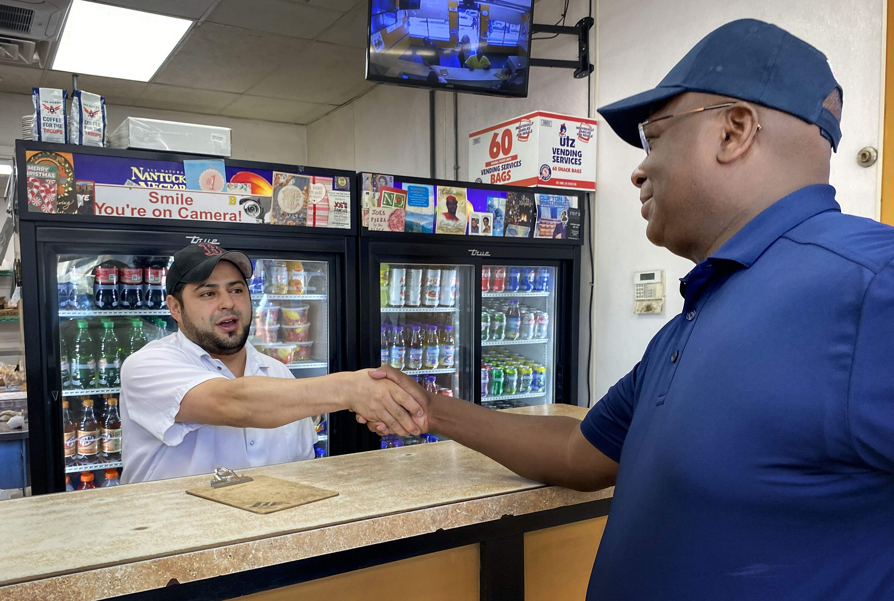 Boston Police Commissioner Michael Cox shakes hands with a local business owner in Roxbury during a community outreach initiative aimed at understanding residents' needs and mitigating crime. (Deborah Becker/WBUR)