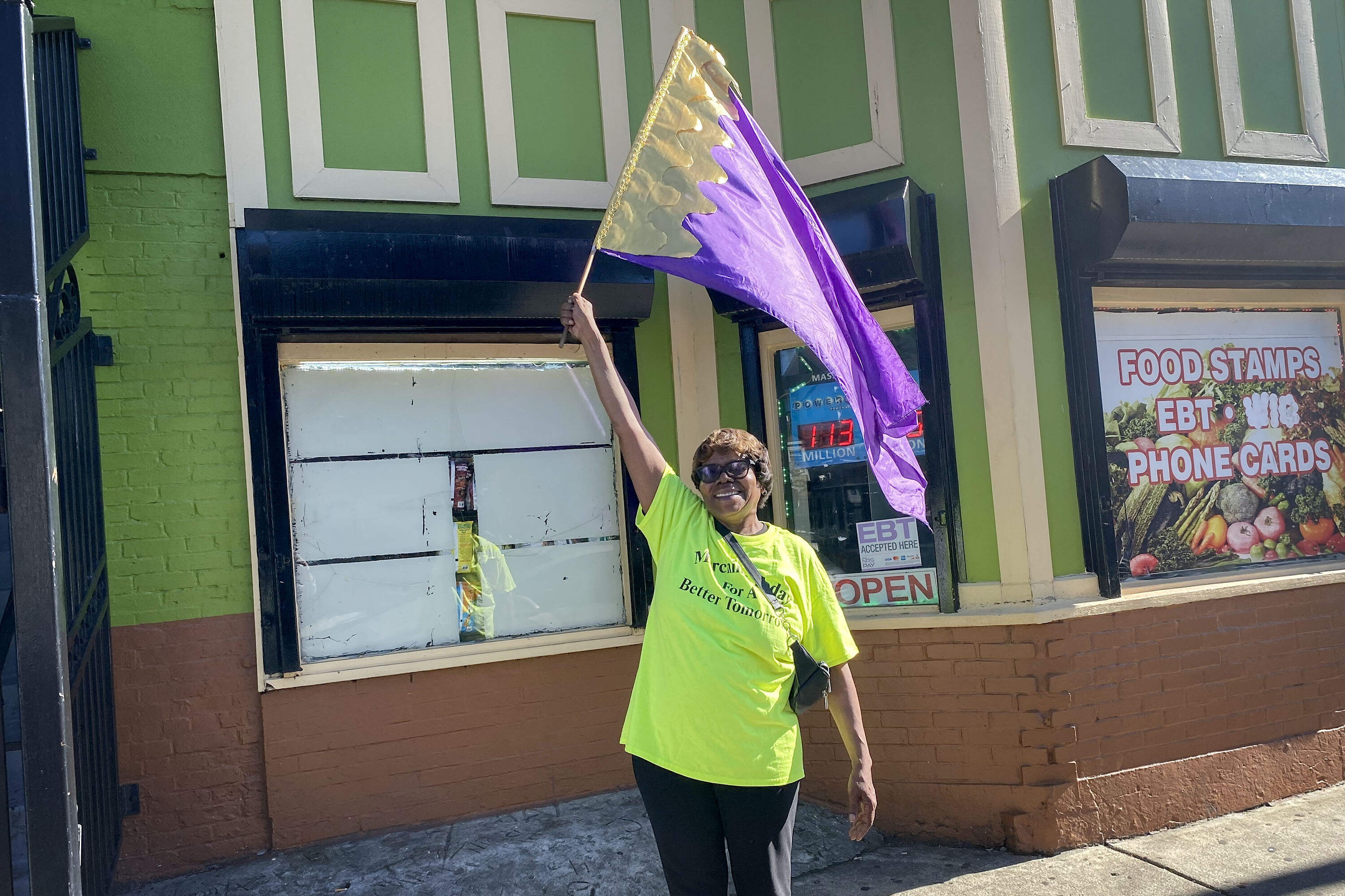 Roxbury resident Catherine Quaratiello joined the peace walk, waving a purple flag that represents Christian worship. She sees the walks as a way to promote peace in the neighborhood. (Deborah Becker/WBUR)